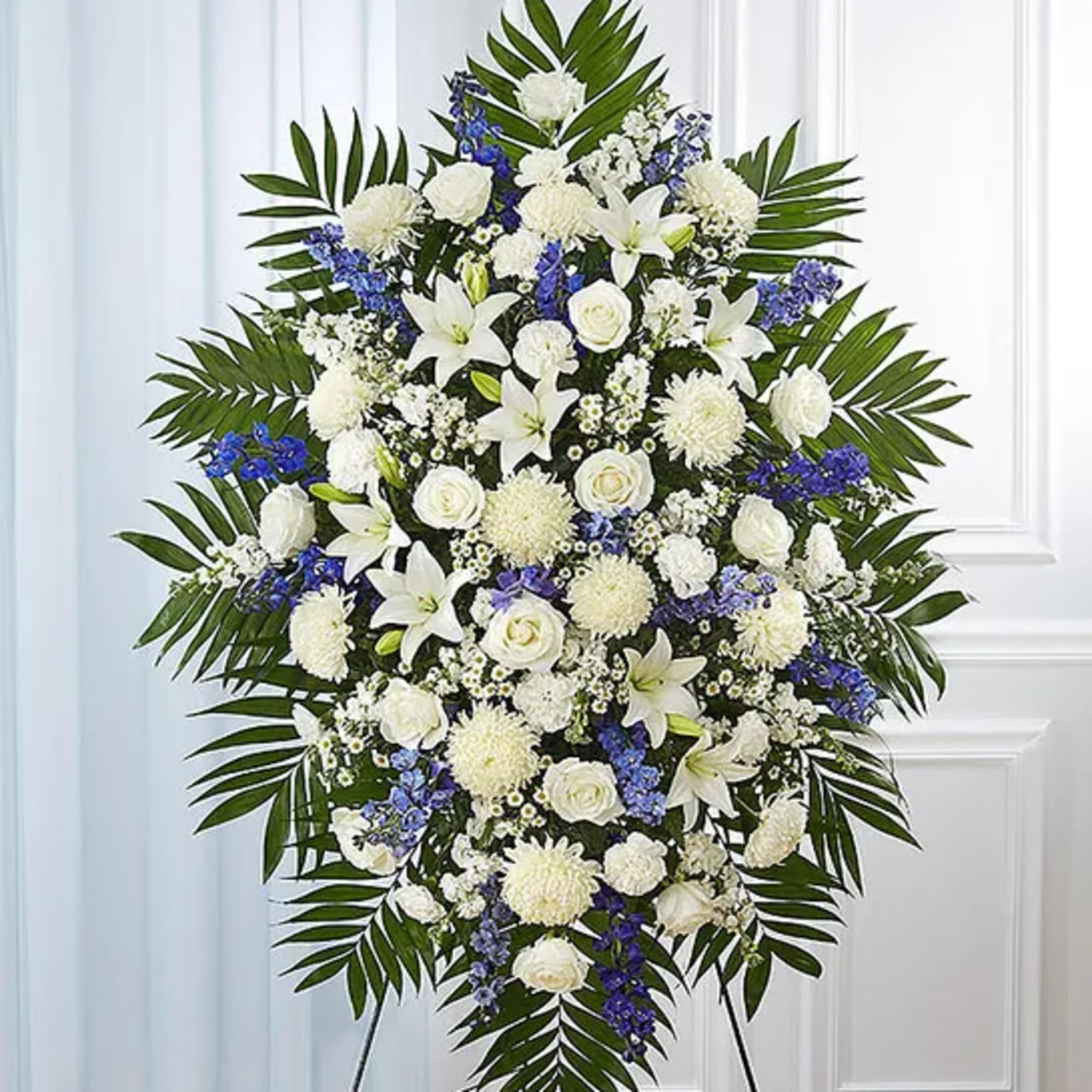 Standing funeral spray of white and blue flowers with palm fronds