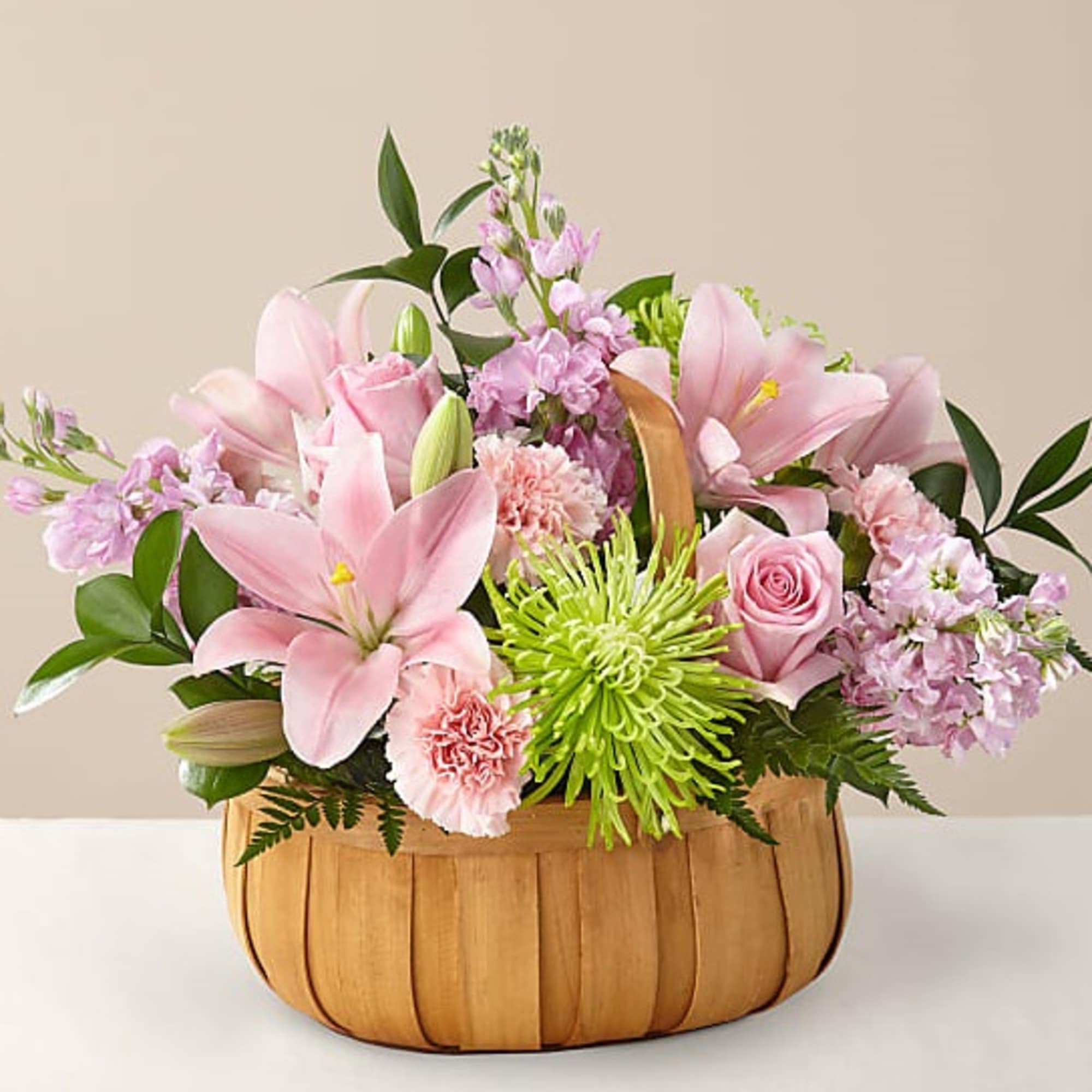 Pink lilies and roses arranged in a wooden basket