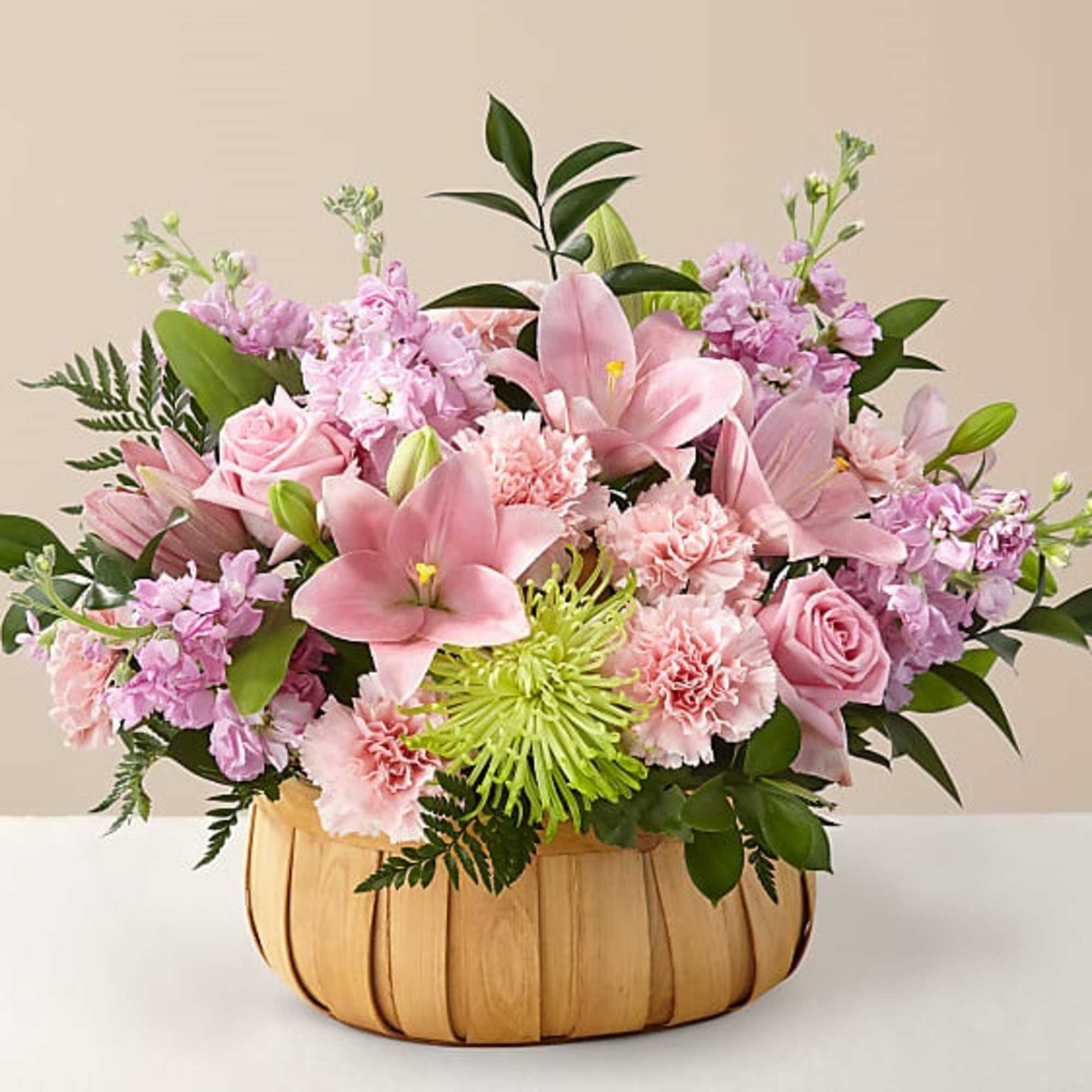 Pink lilies, roses, and carnations in a wooden basket