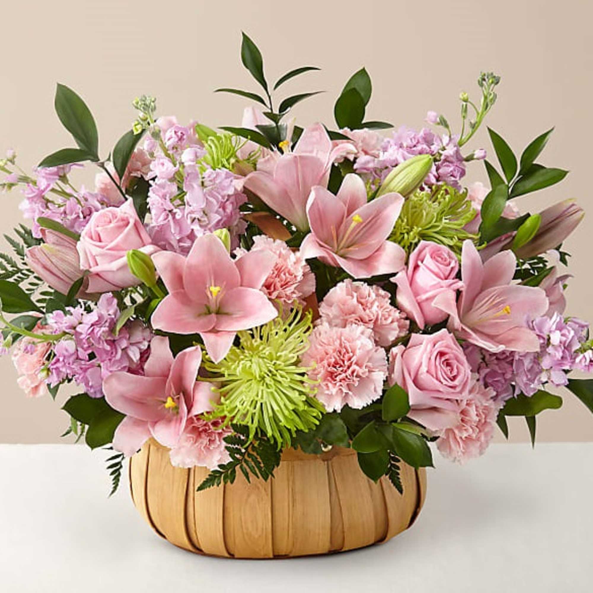 Pink lilies, roses, and carnations in a woven basket