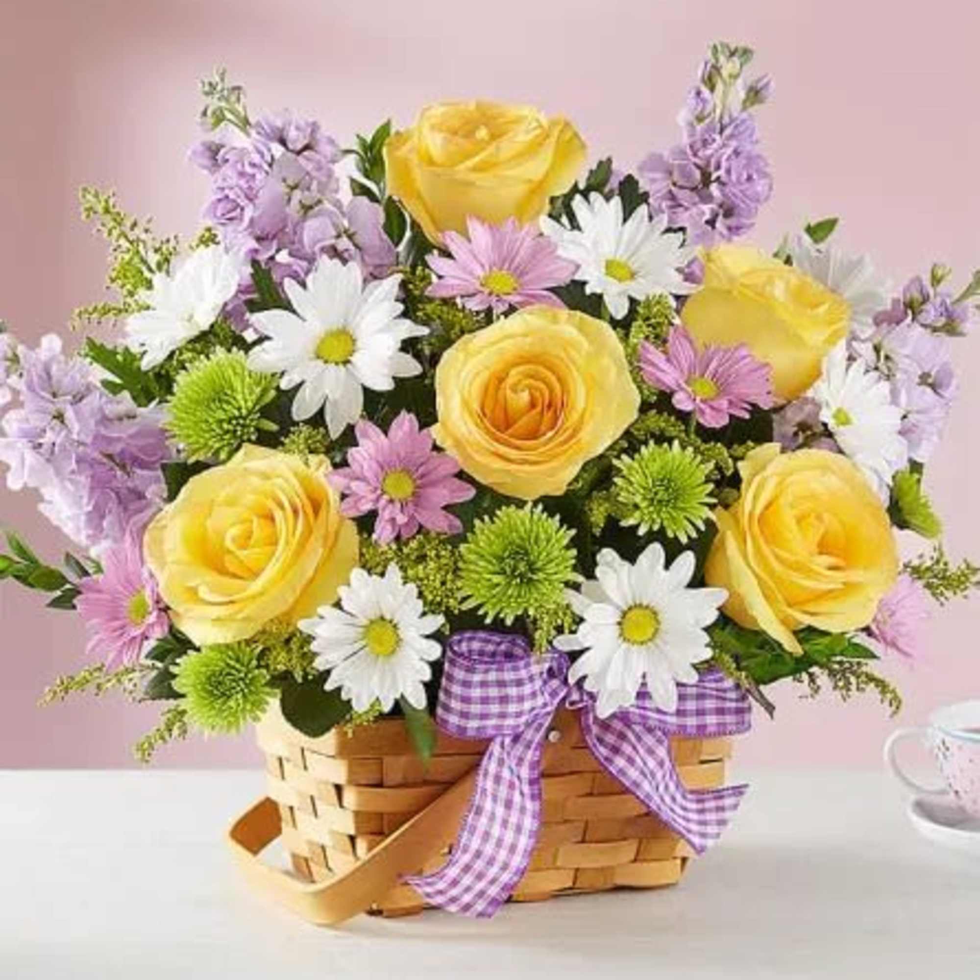 Basket arrangement of yellow roses, white daisies, and purple flowers with a ribbon