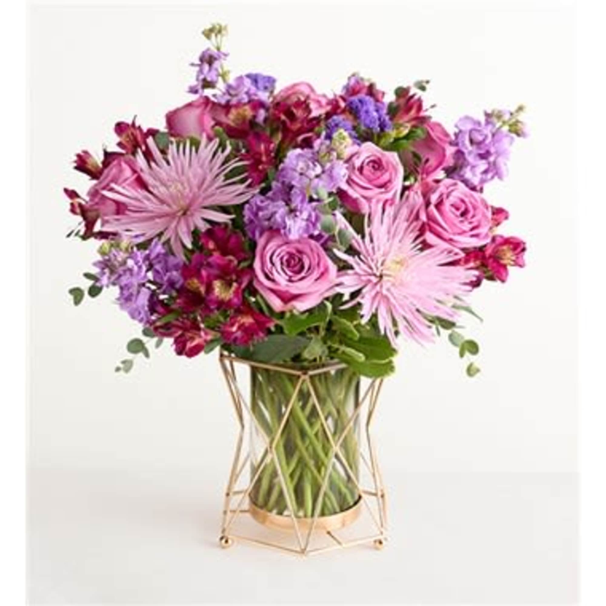 Pink and purple bouquet in a clear vase with a gold stand
