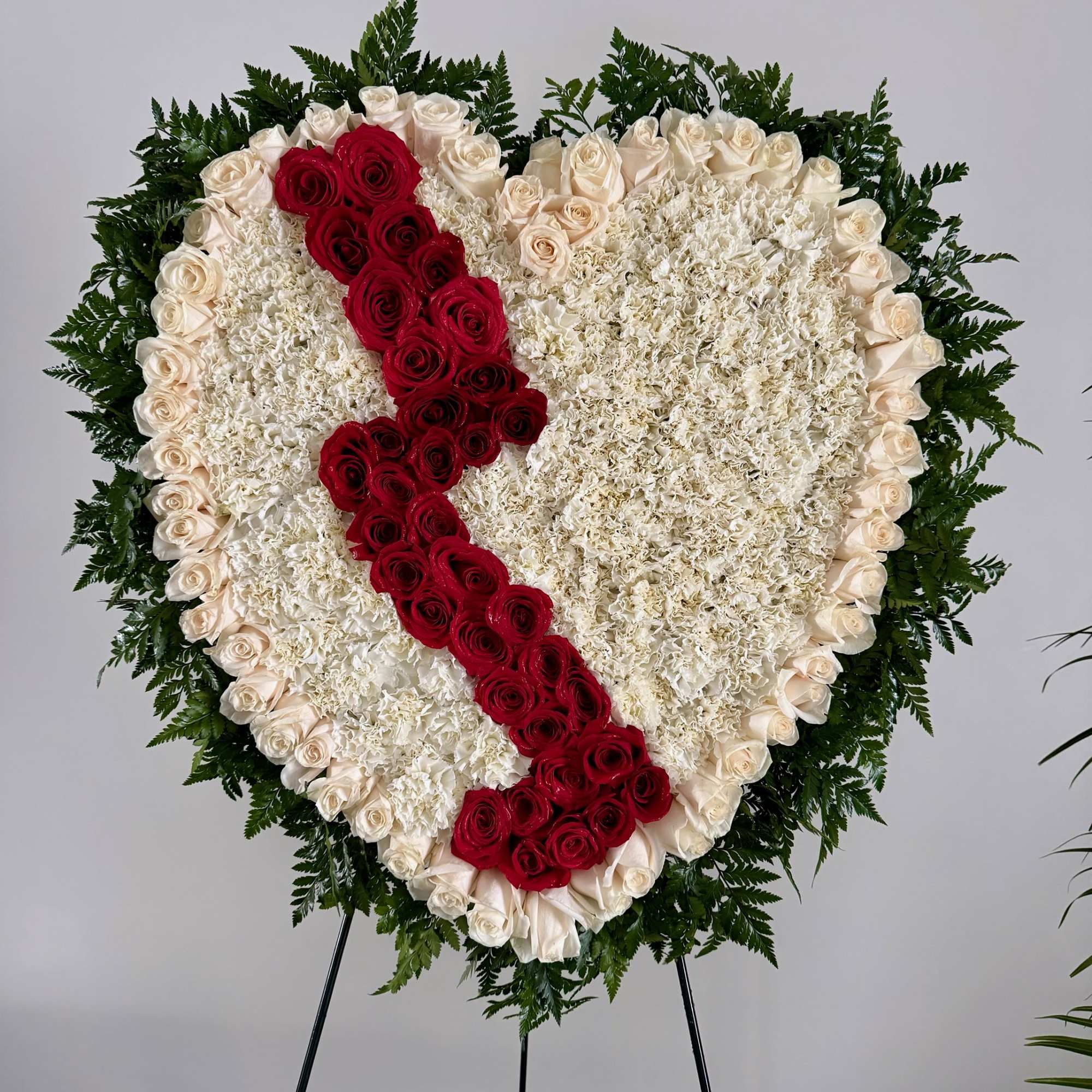 Heart-shaped floral tribute with red and white roses on an easel