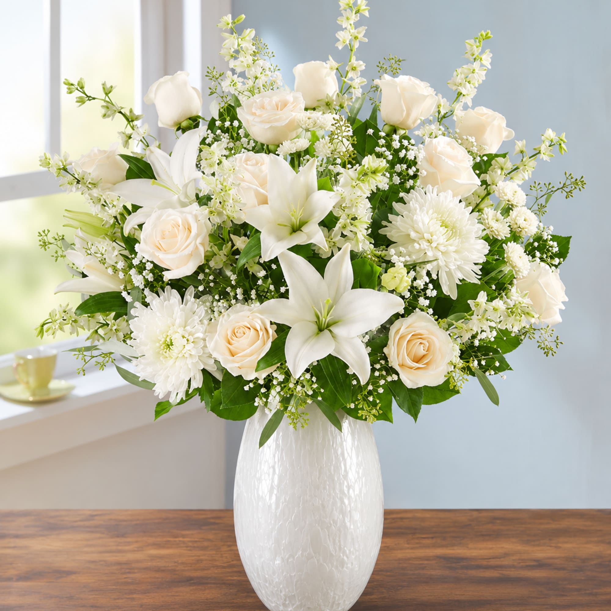Pure white lilies and roses arranged with crisp greenery create a serene