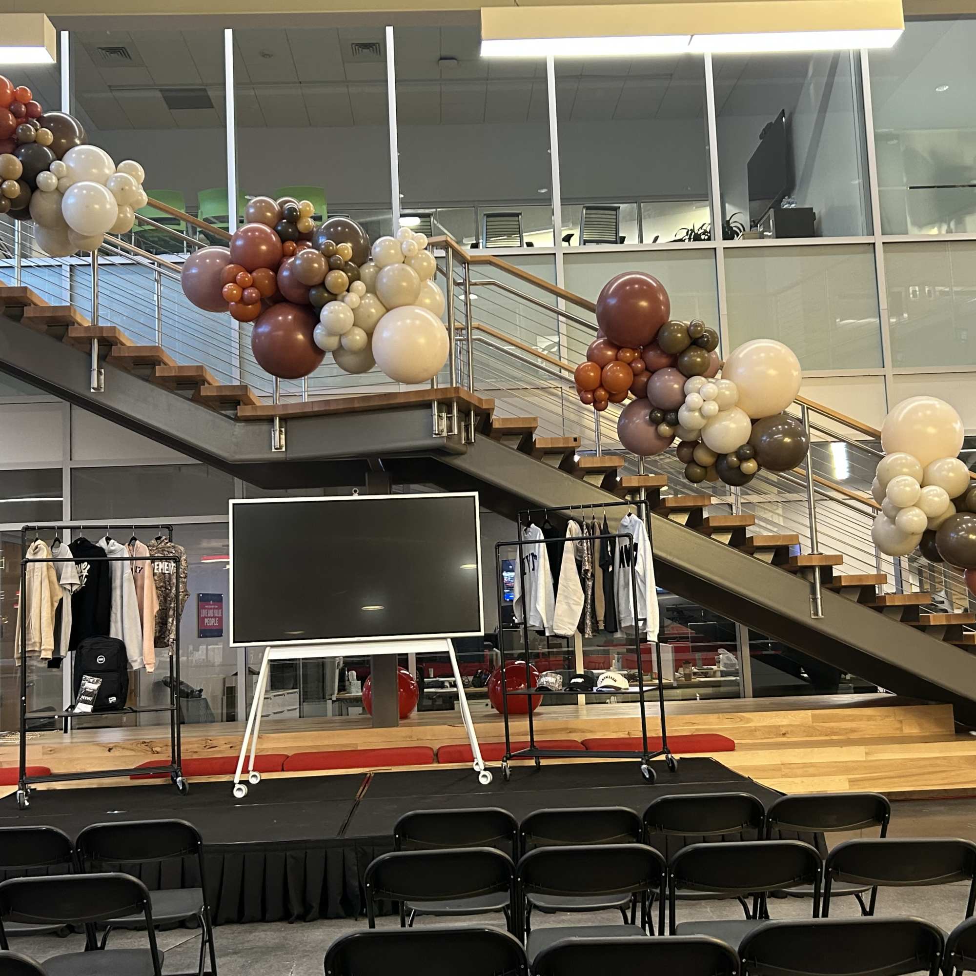 Balloon clusters decorate a staircase in an indoor event space.
