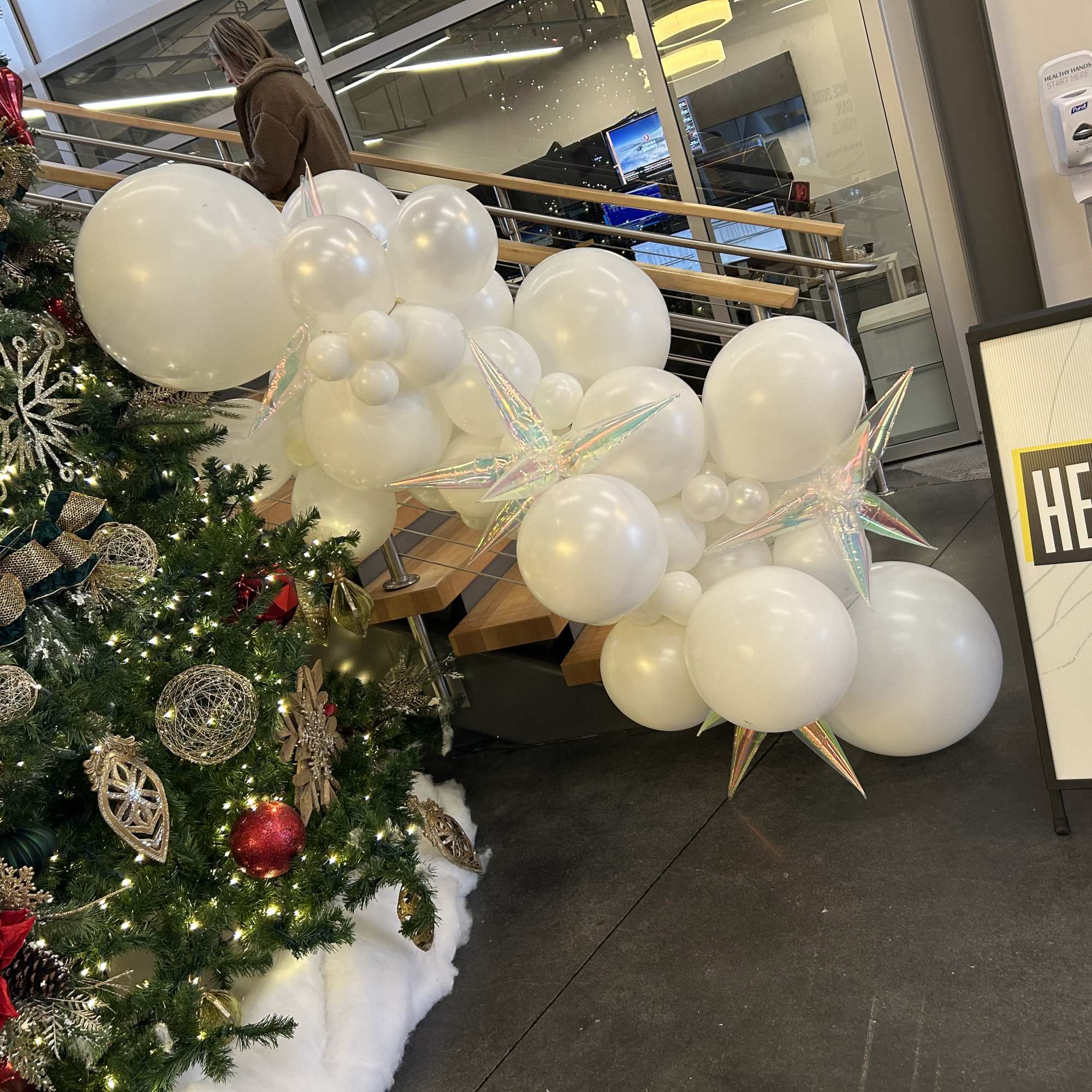 White balloon cluster beside a decorated Christmas tree in a lobby