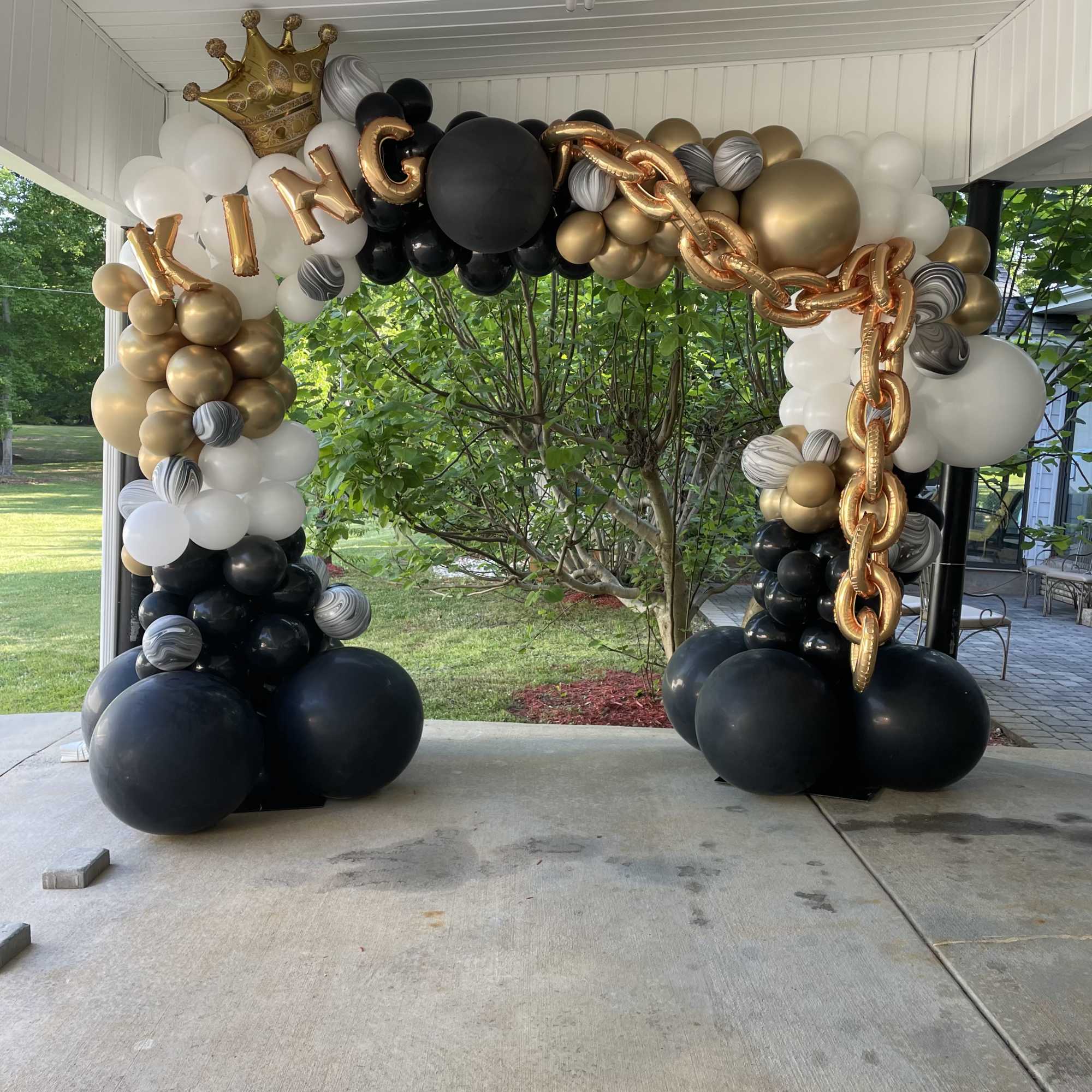 Black, white, and gold balloon arch with a crown and "KING" letters