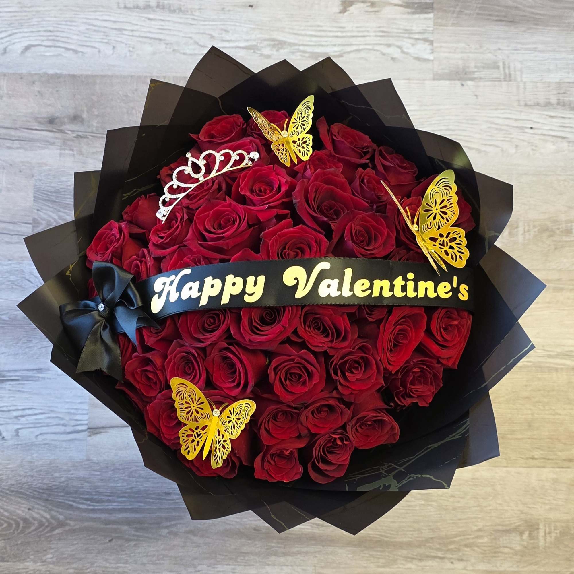 Bouquet of red roses wrapped in black paper with a Valentine’s ribbon
