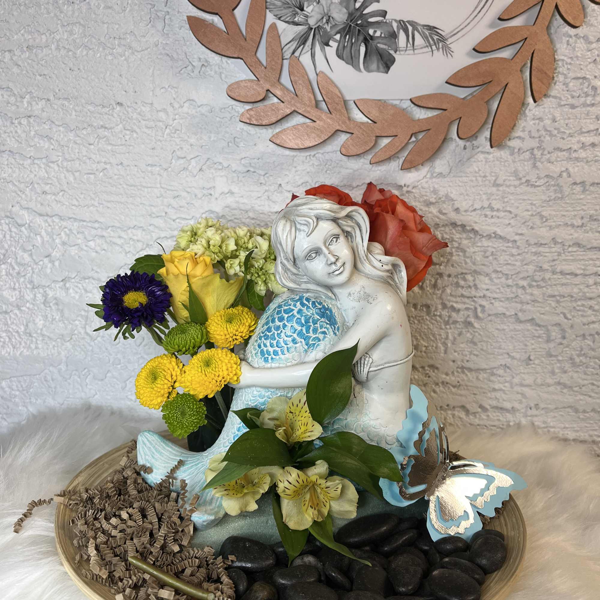 Floral arrangement with a mermaid figurine, roses, and chrysanthemums on a tray