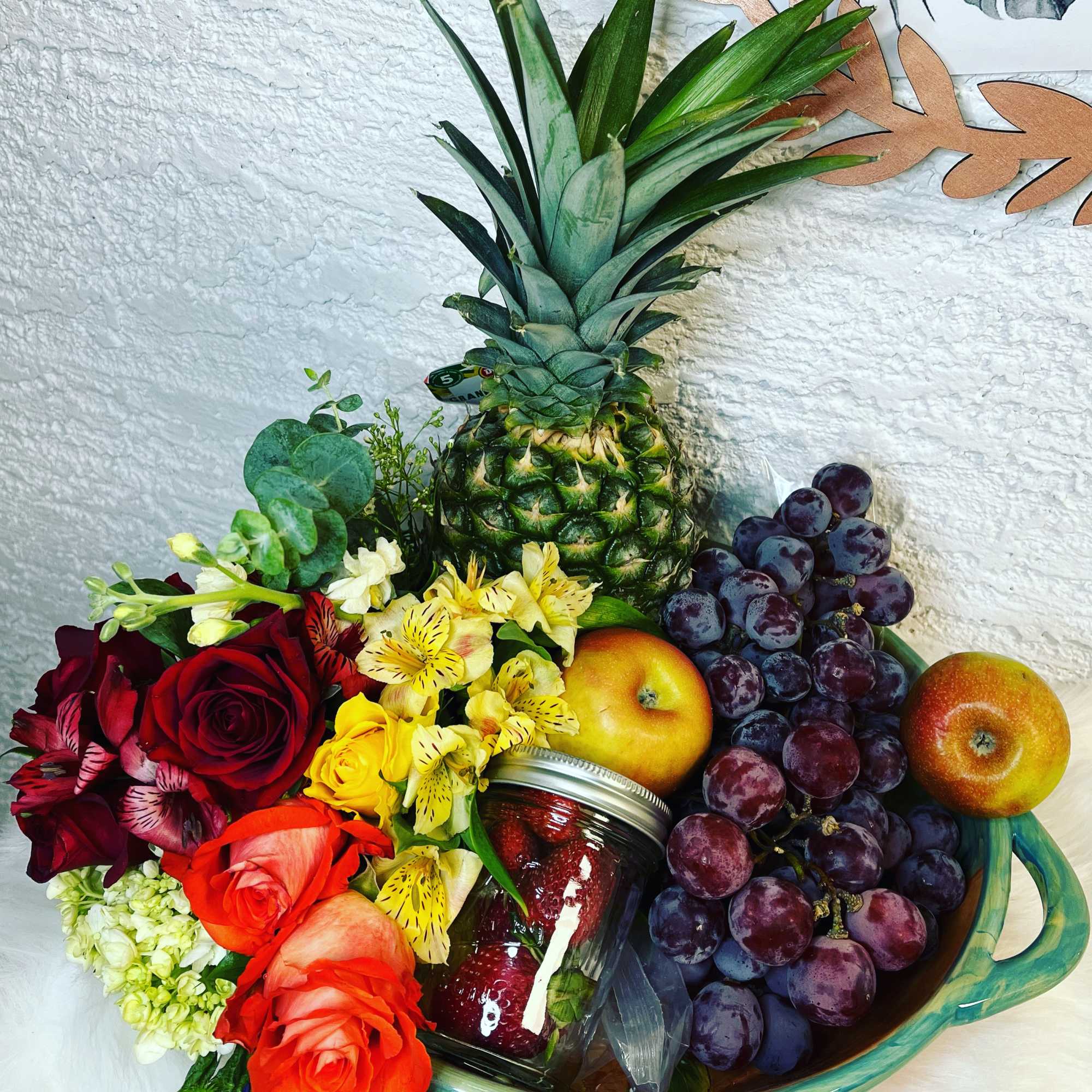 Fruit basket with roses, grapes, pineapple, apples, and a jar of strawberries