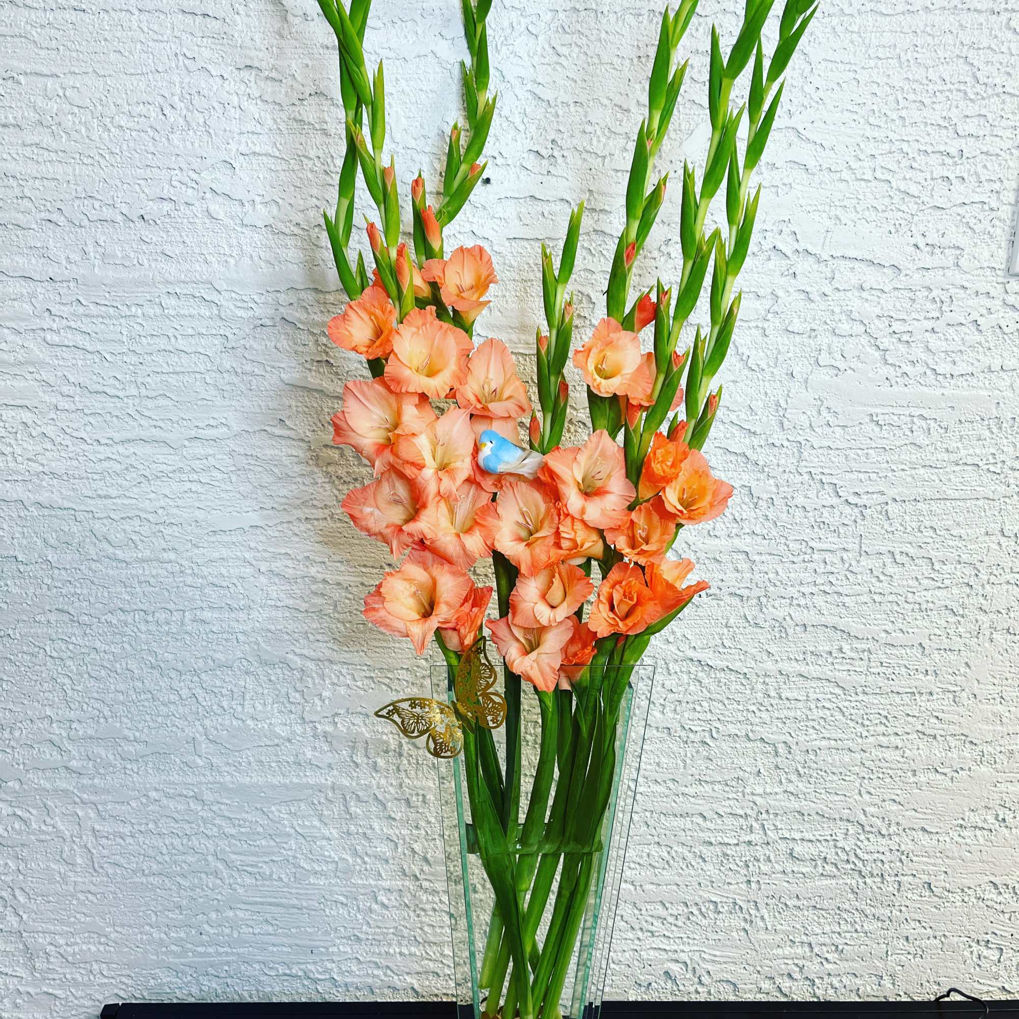 Tall peach gladiolus arrangement in a clear glass vase