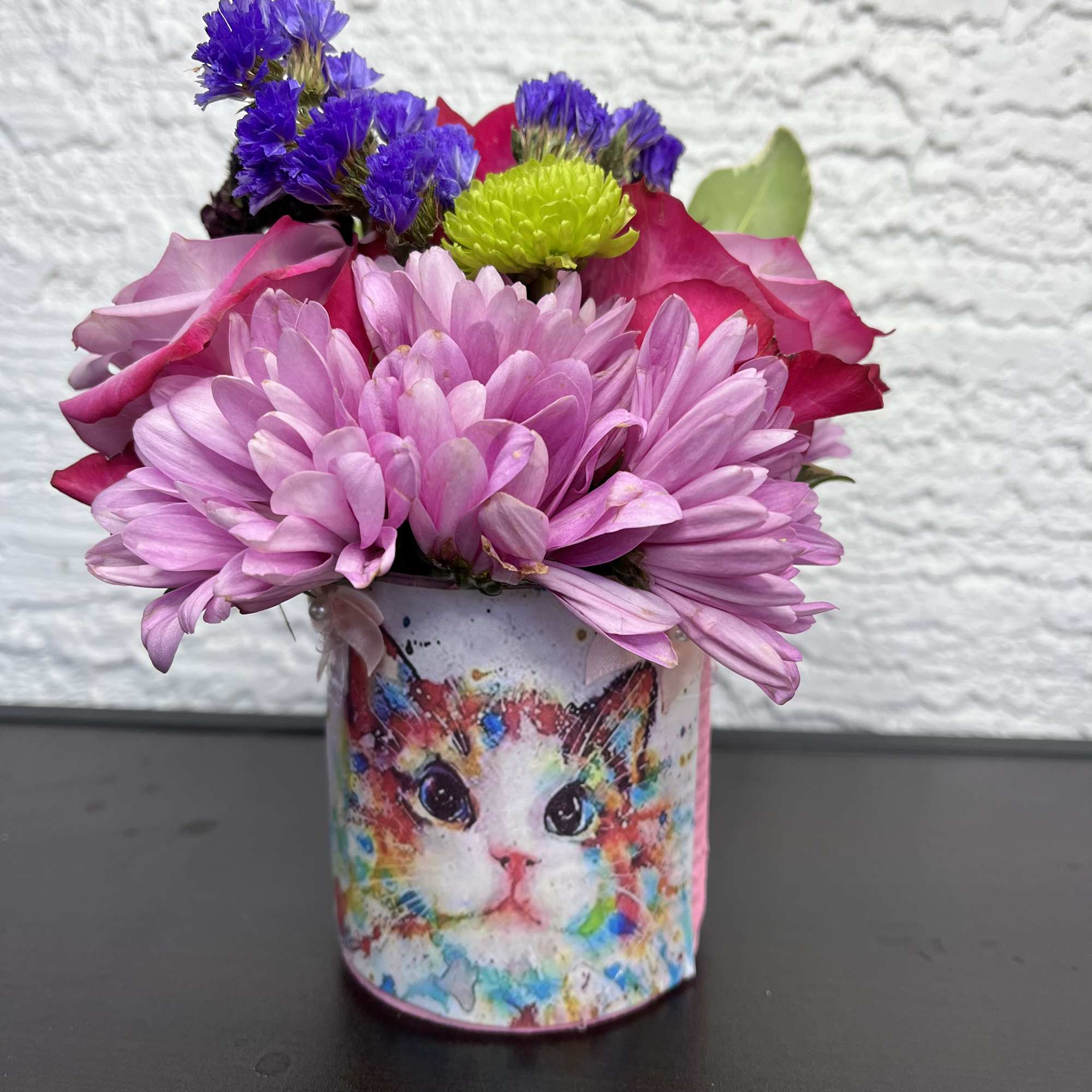 Pink and purple flowers in a cat-printed tin container