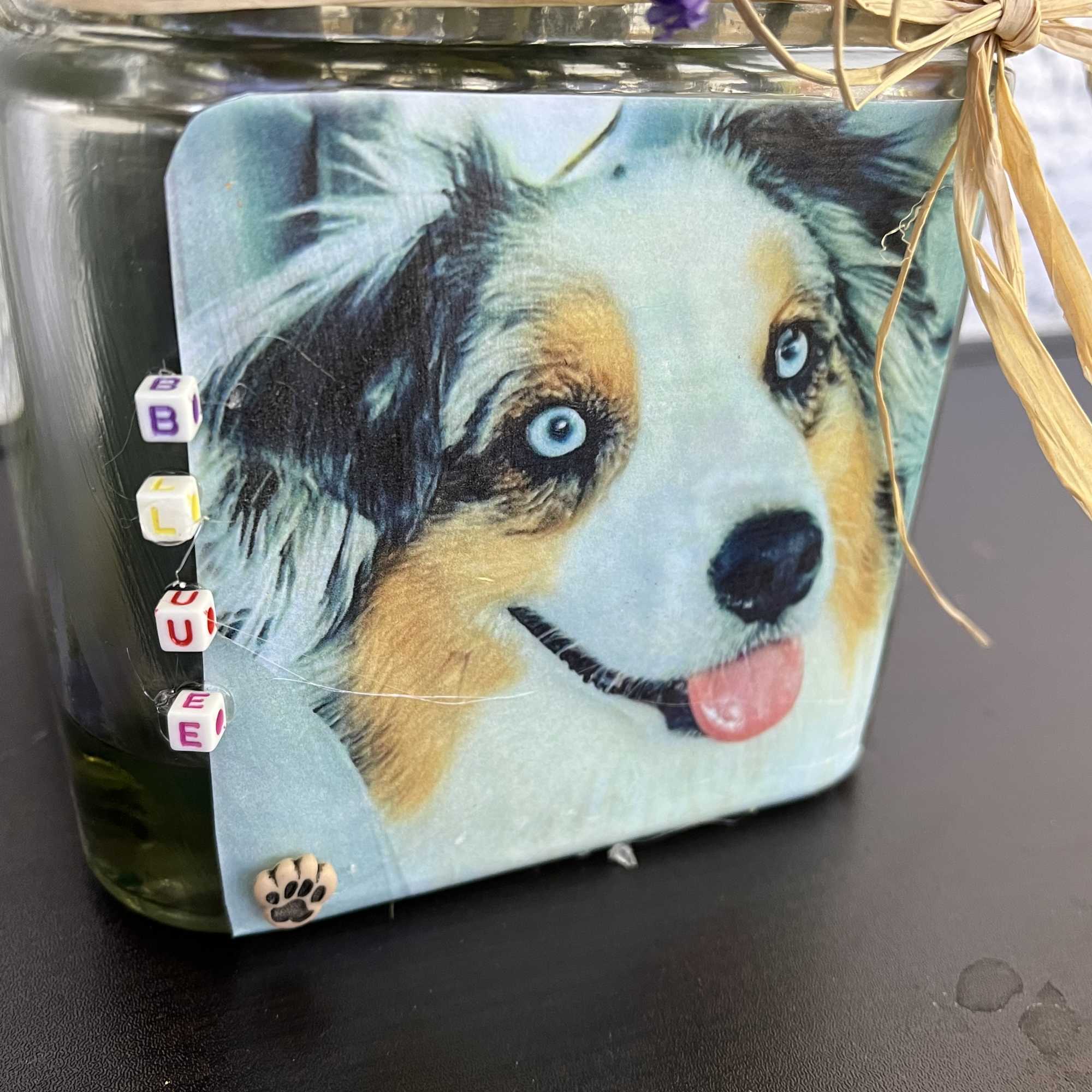 Glass jar with a dog photo label and purple flowers tied on top