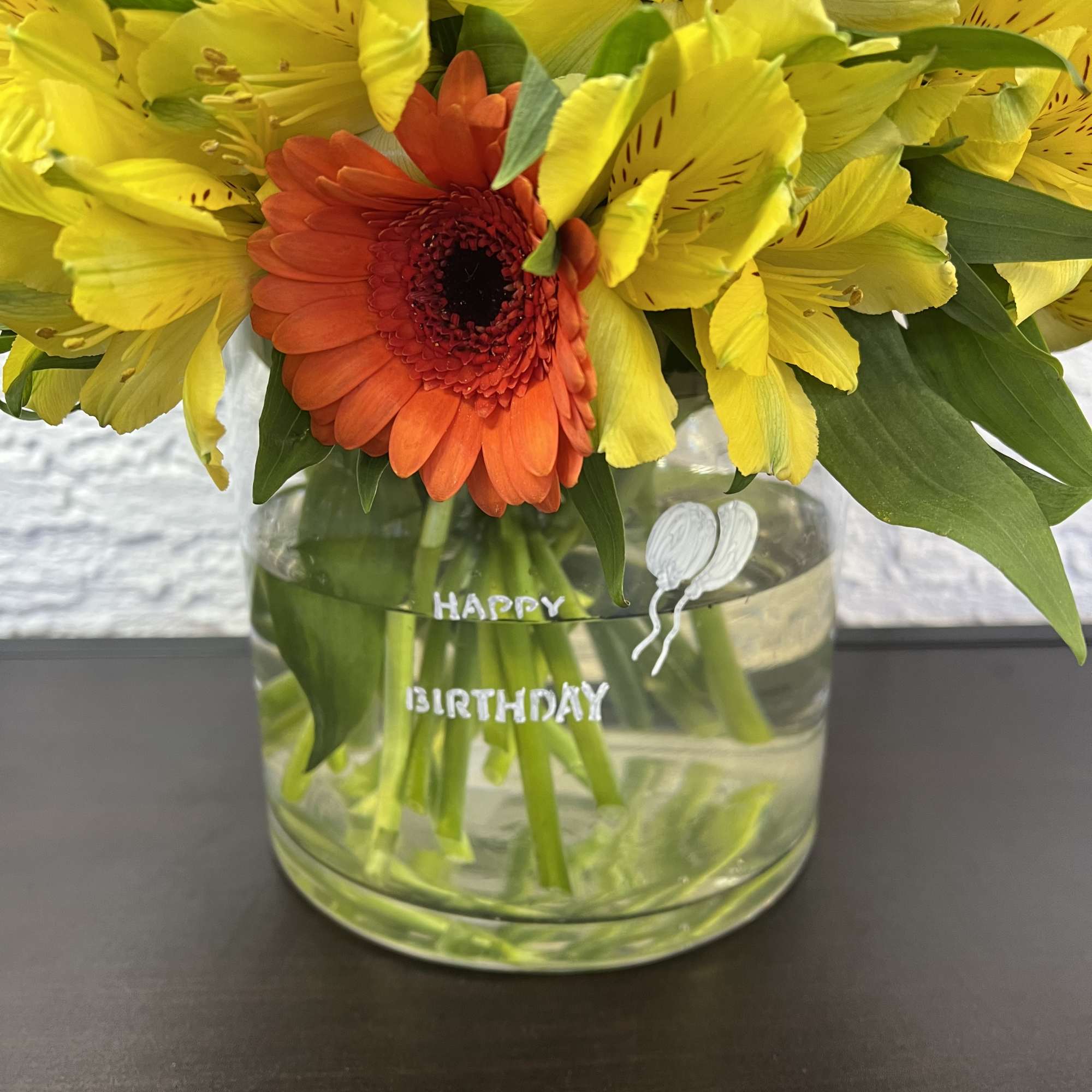 Yellow and orange gerbera daisies in a clear glass vase