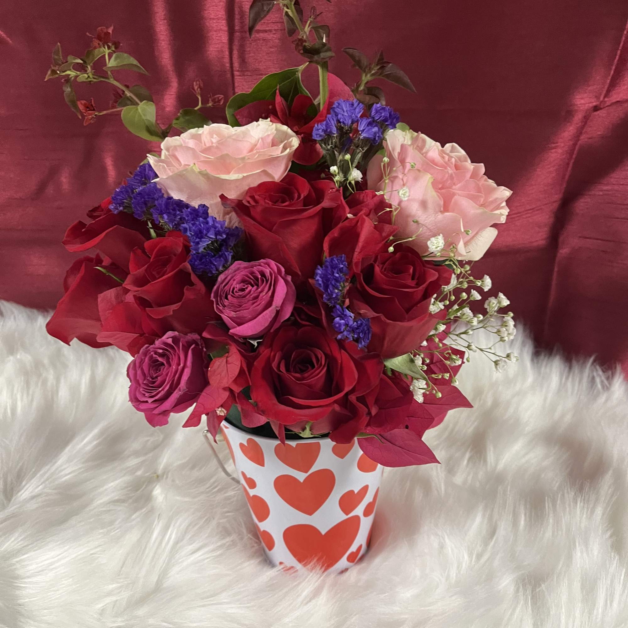 Bouquet of red and pink roses in a heart-patterned vase