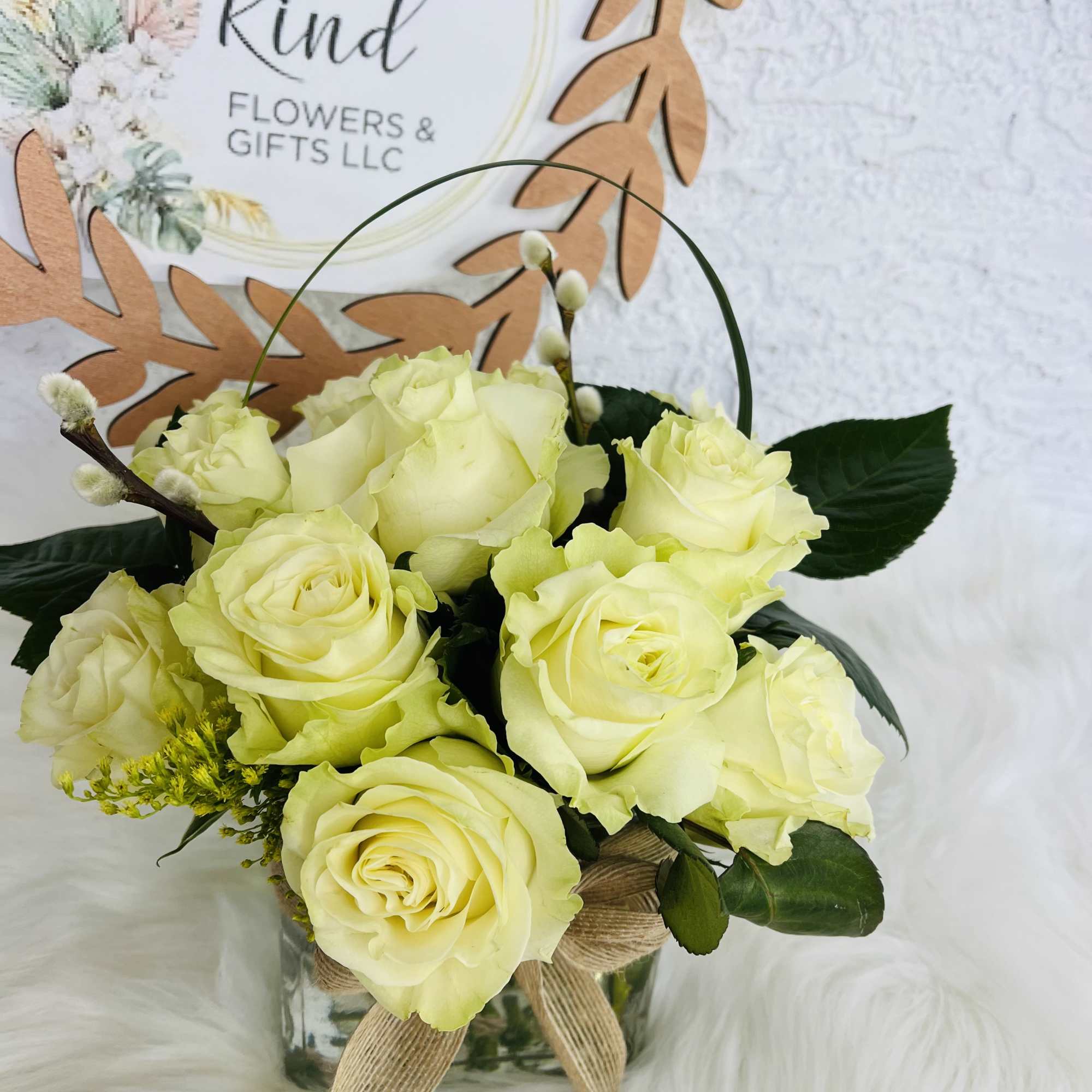 Pale yellow roses arranged in a glass vase with a burlap bow