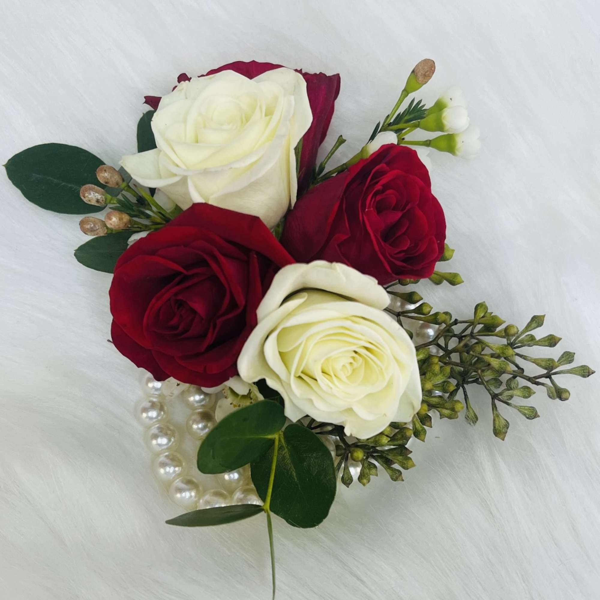 Small bouquet of red and white roses with greenery and pearl accents