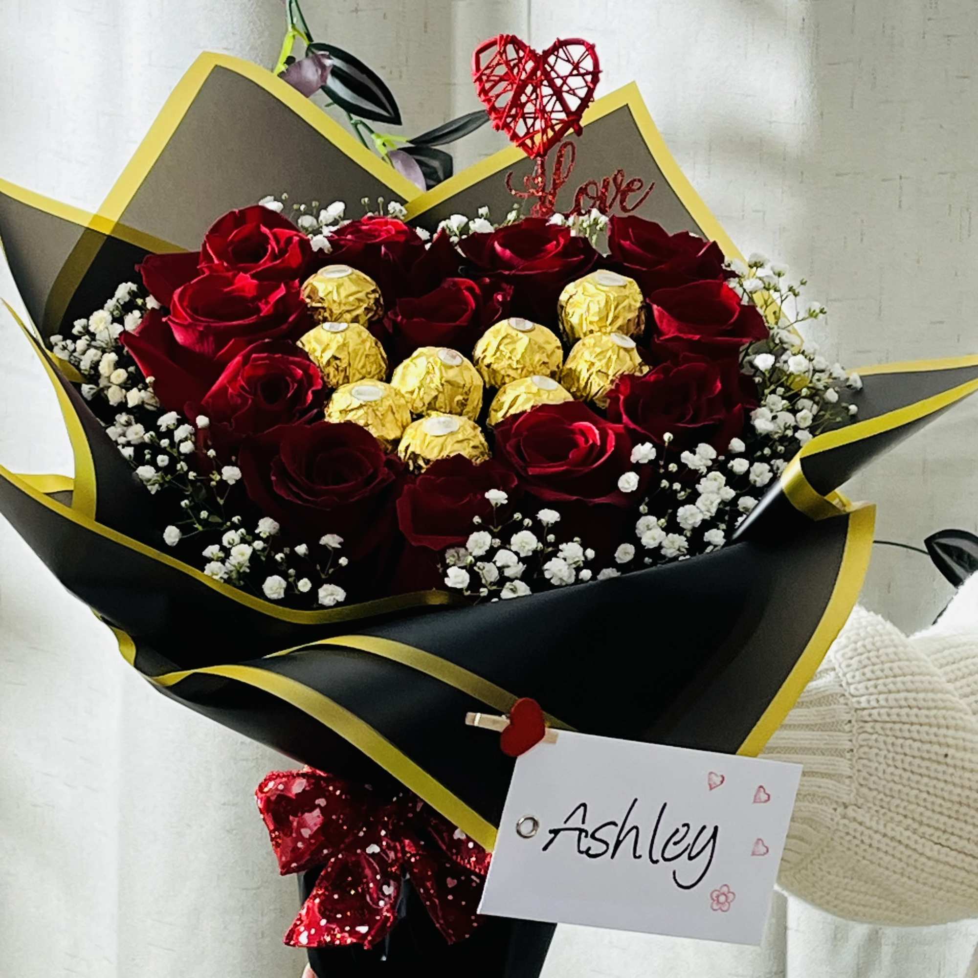 Bouquet of red roses with gold-wrapped chocolates and a heart topper