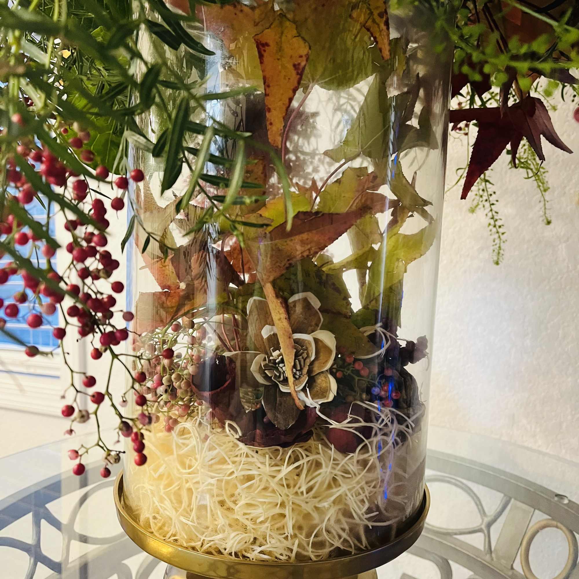 Glass cylinder terrarium with autumn leaves and red berries