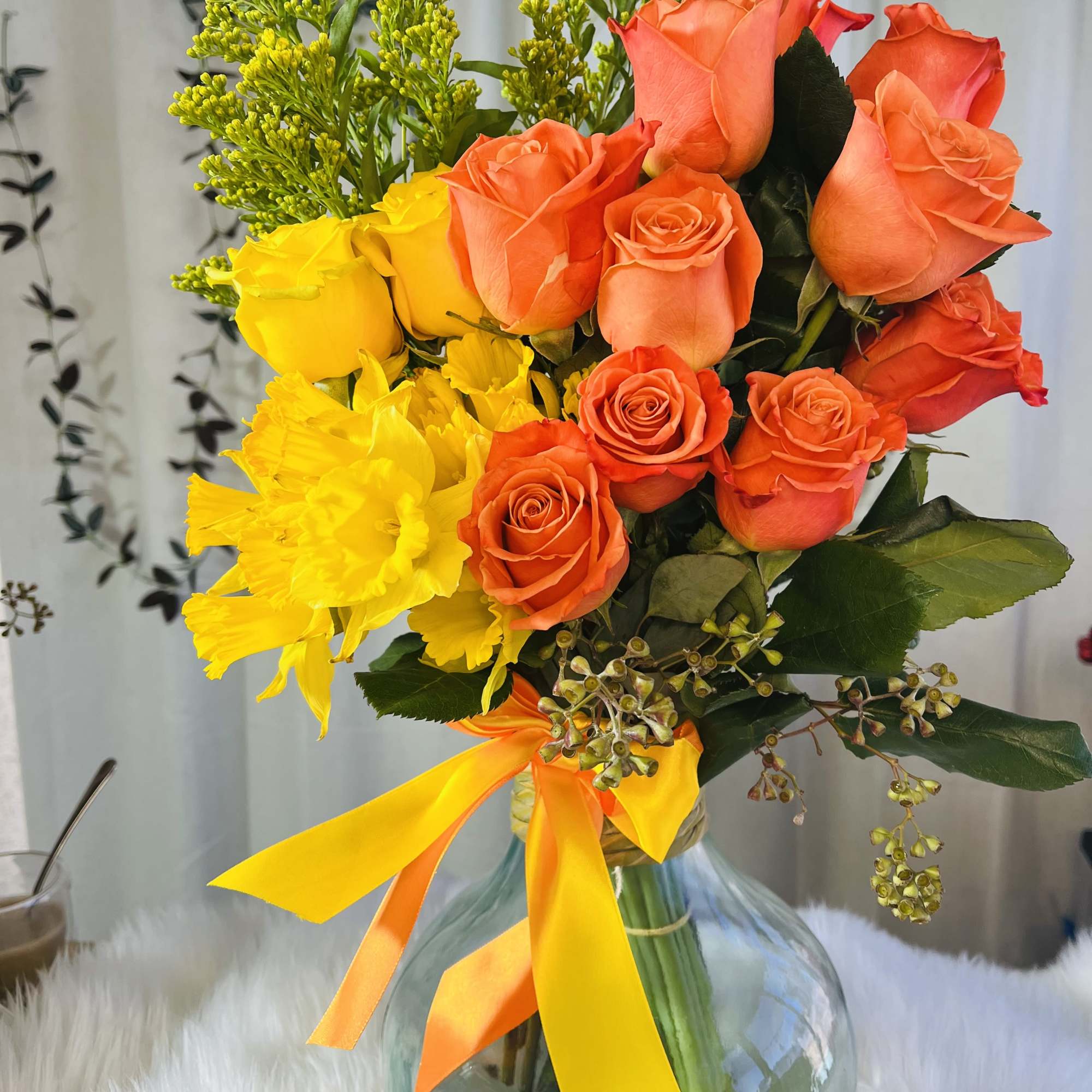 Bouquet of orange and yellow roses in a glass vase with ribbon