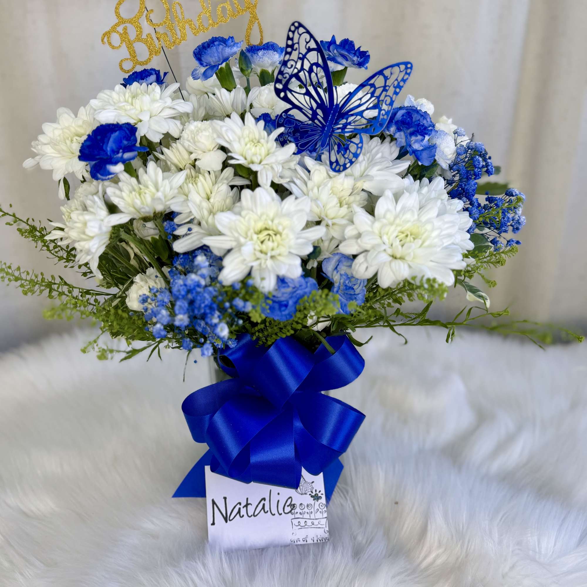 White and blue flower bouquet with a gold Happy Birthday topper