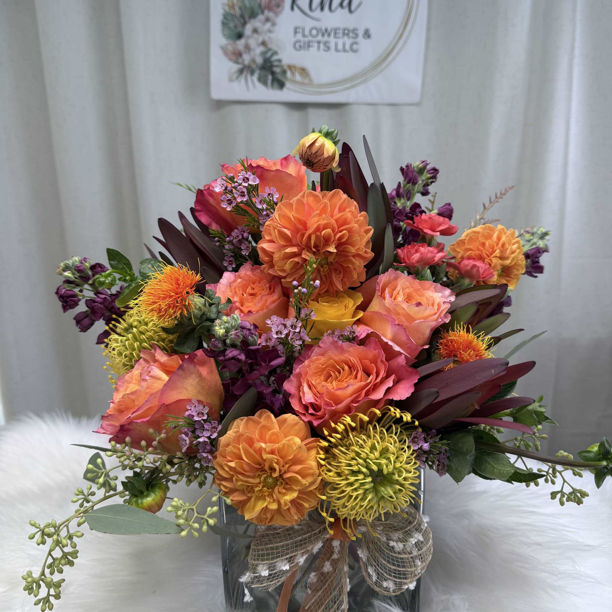 Mixed orange, pink, and purple bouquet in a square glass vase