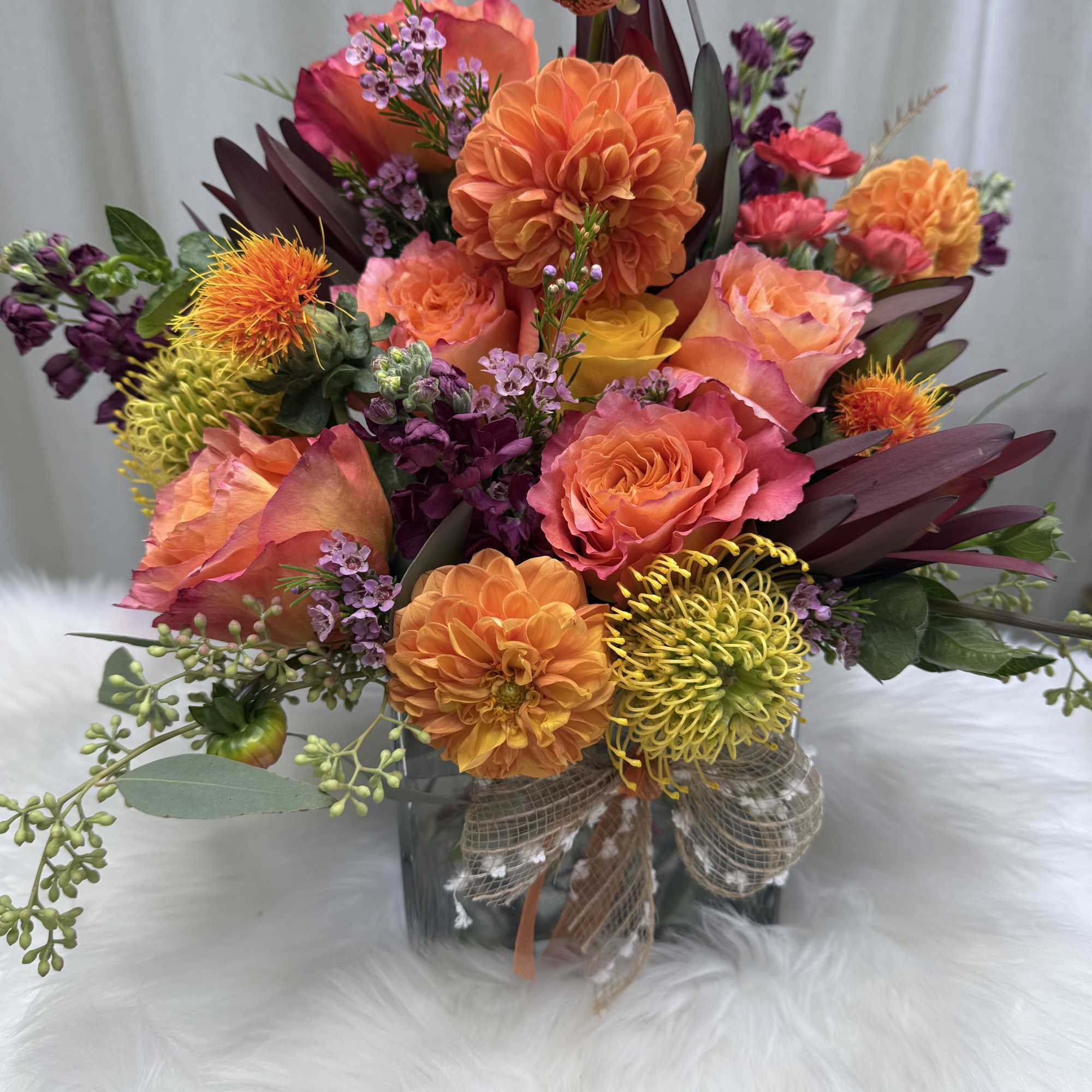 Bright mixed bouquet in a glass vase with orange, pink, and yellow blooms