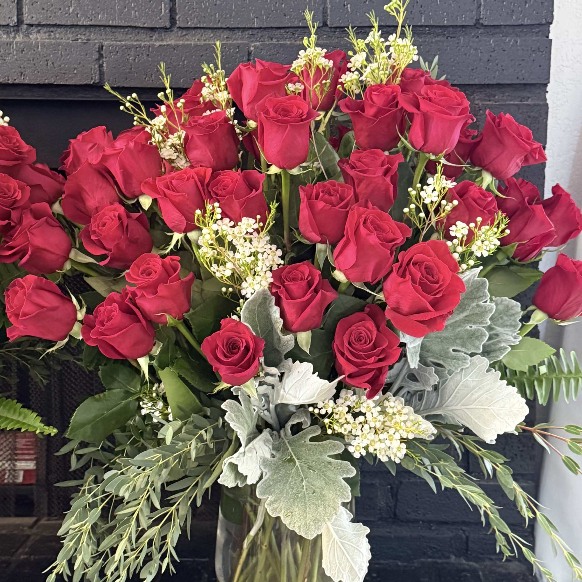 Bouquet of red roses in a clear glass vase with silver foliage