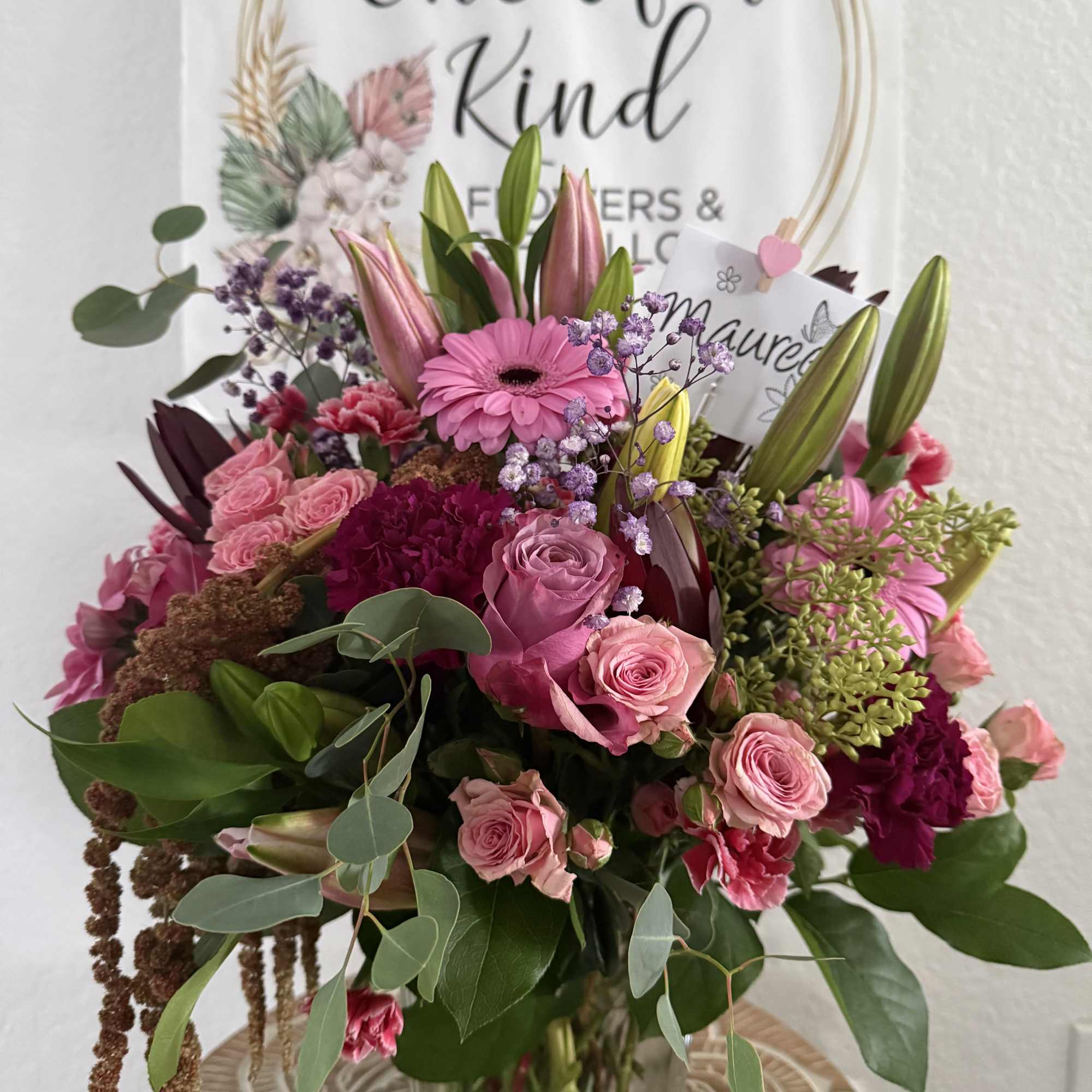 Pink mixed flower bouquet in a glass vase with a gift card