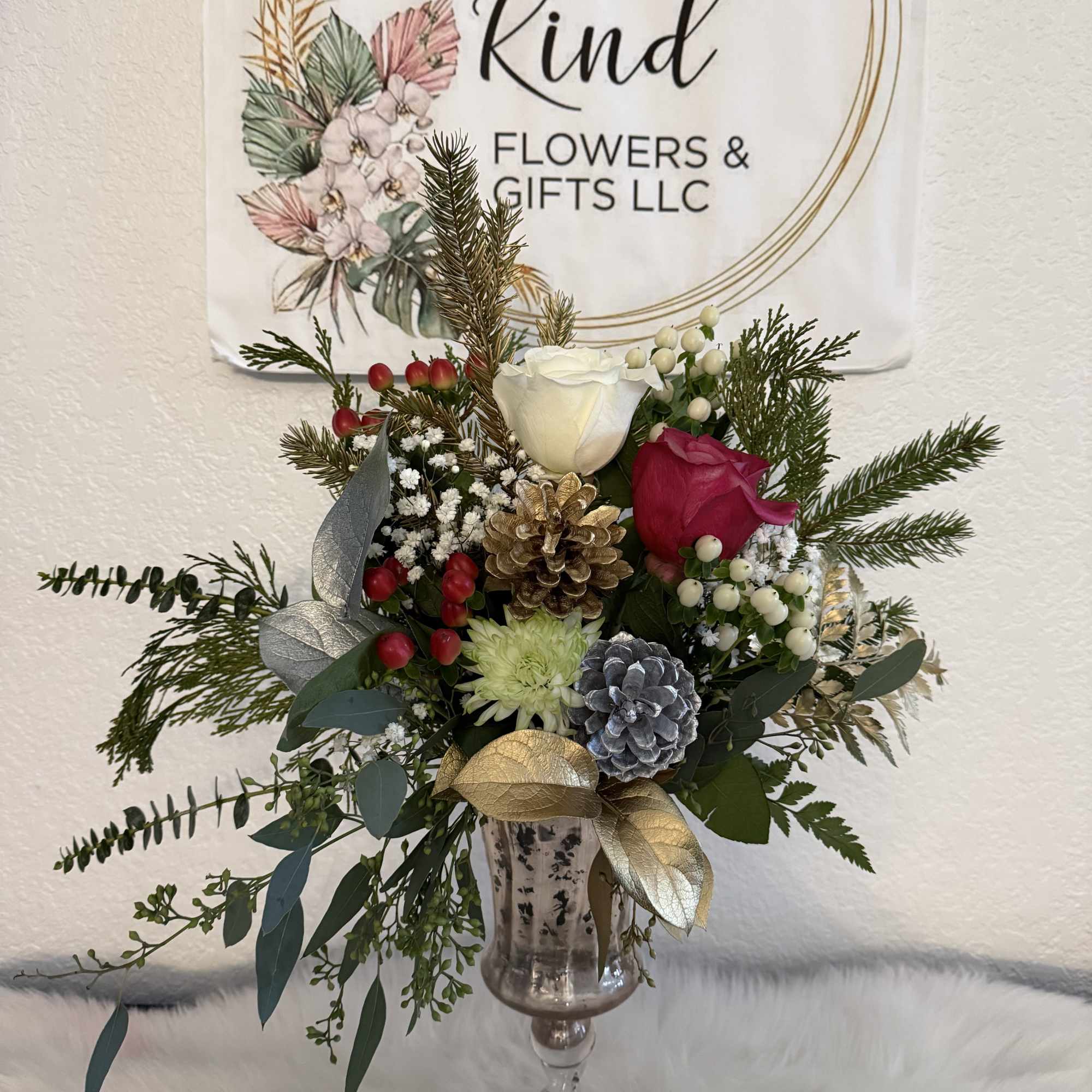 Holiday bouquet in a glass vase with roses, pinecones, and evergreen sprigs
