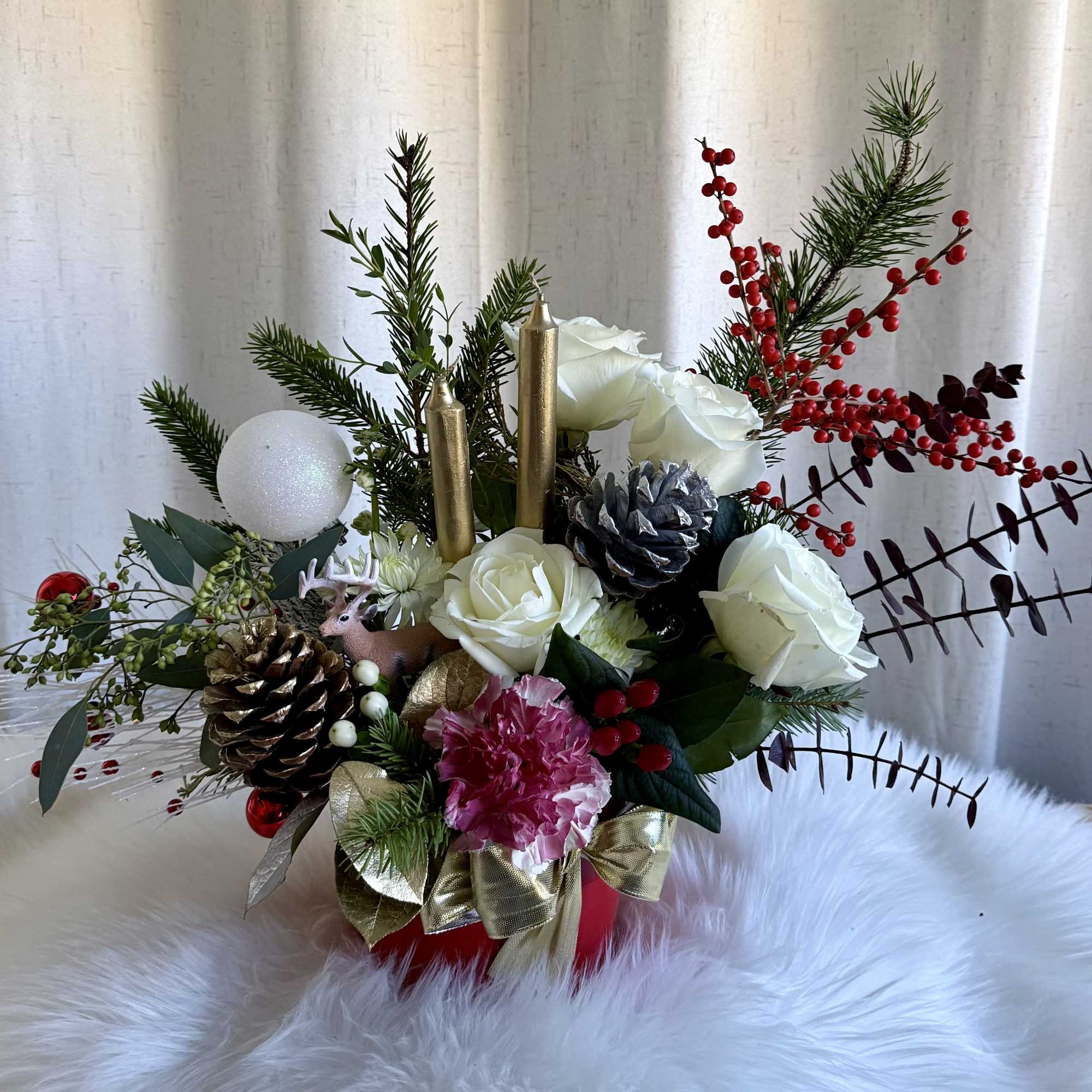 Holiday arrangement with white roses, pinecones, and red berries