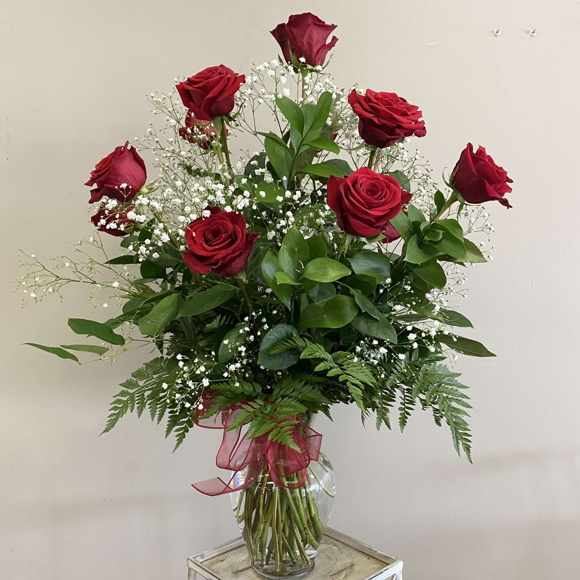 A dozen long stem red roses with baby's breath and assorted greenery