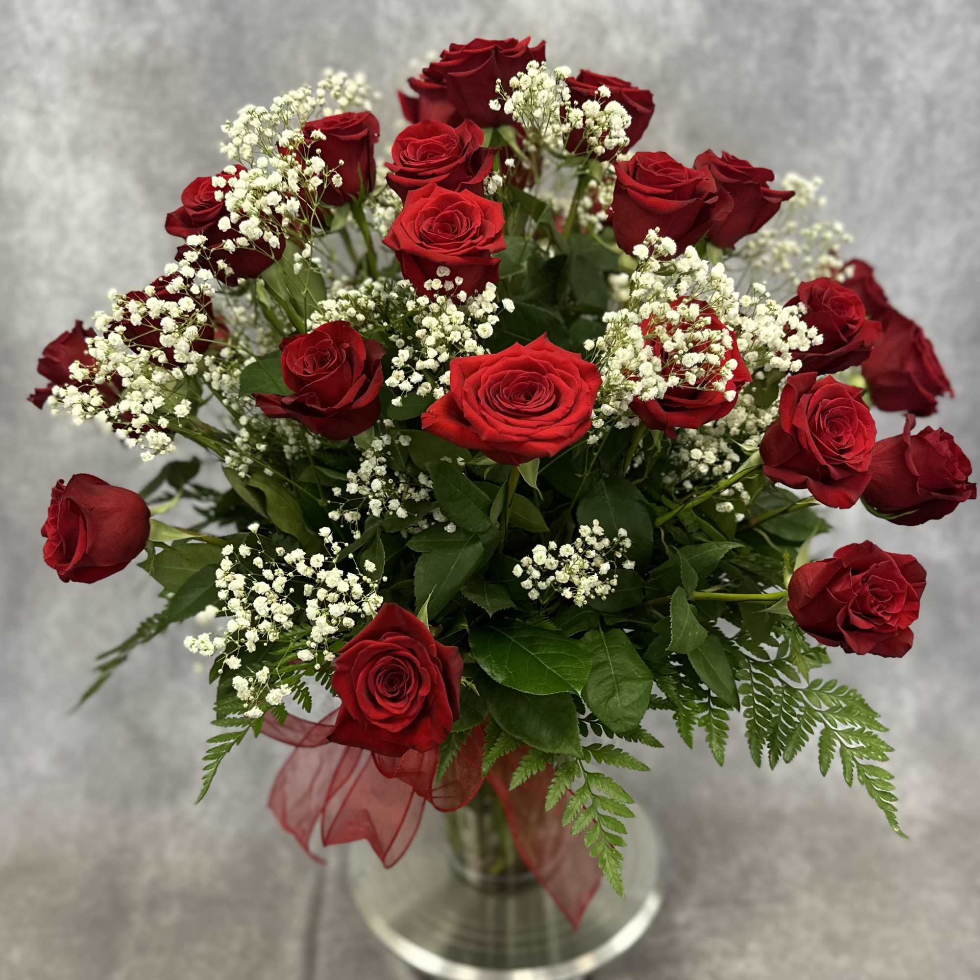 A dozen long stem red roses with baby's breath and assorted greenery
