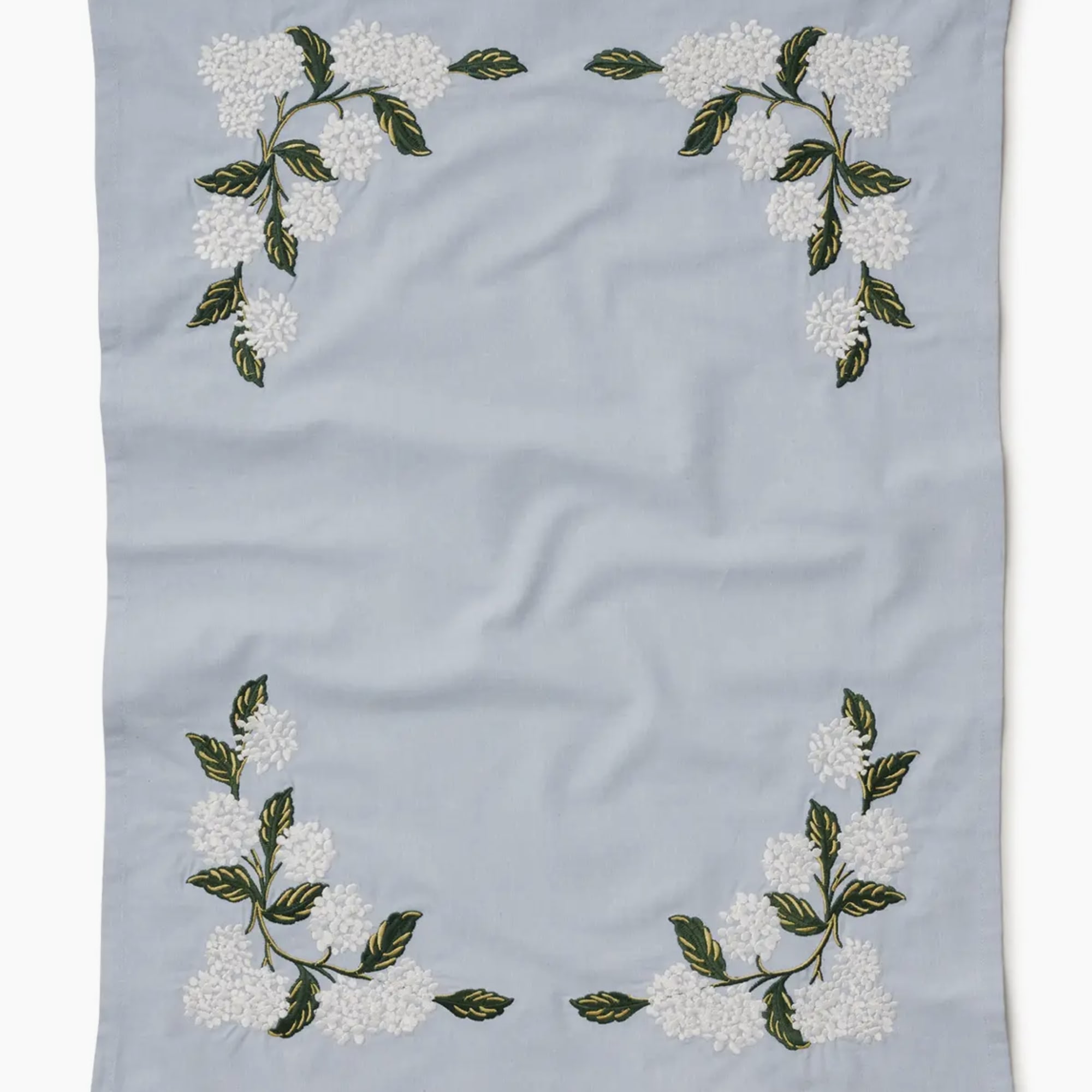 Light blue embroidered cloth with white floral corner motifs