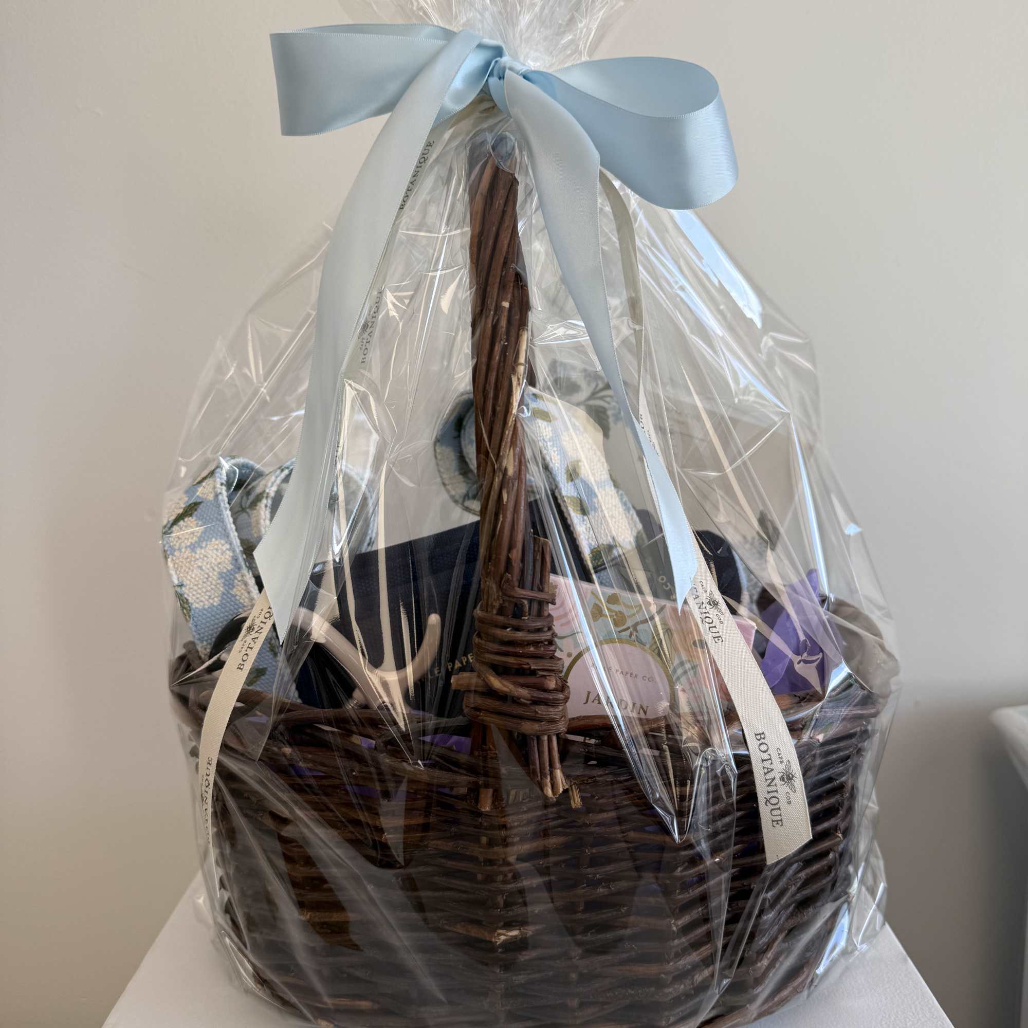 Wrapped gift basket with a blue ribbon and assorted packaged items