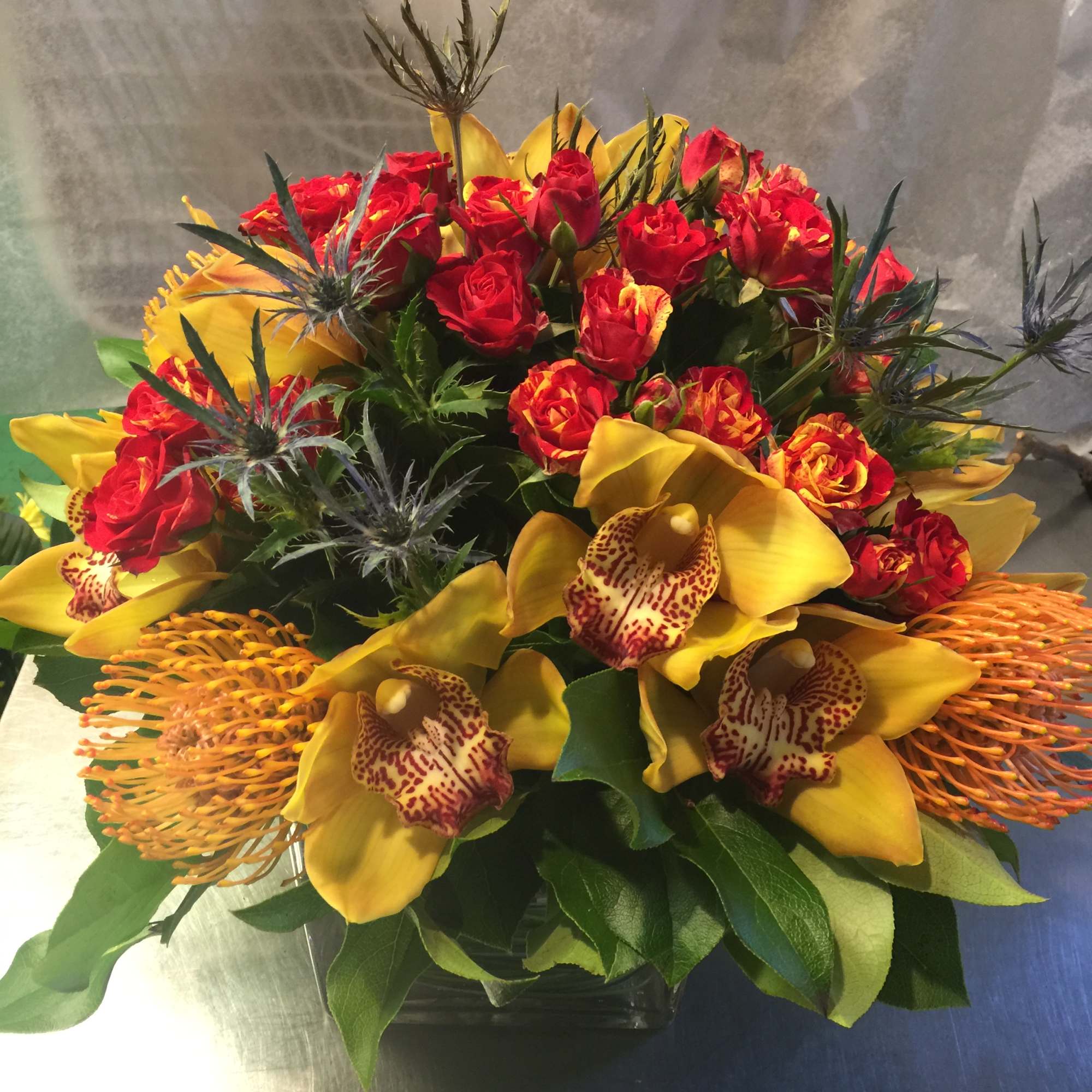 Bouquet of red roses and yellow orchids in a glass vase