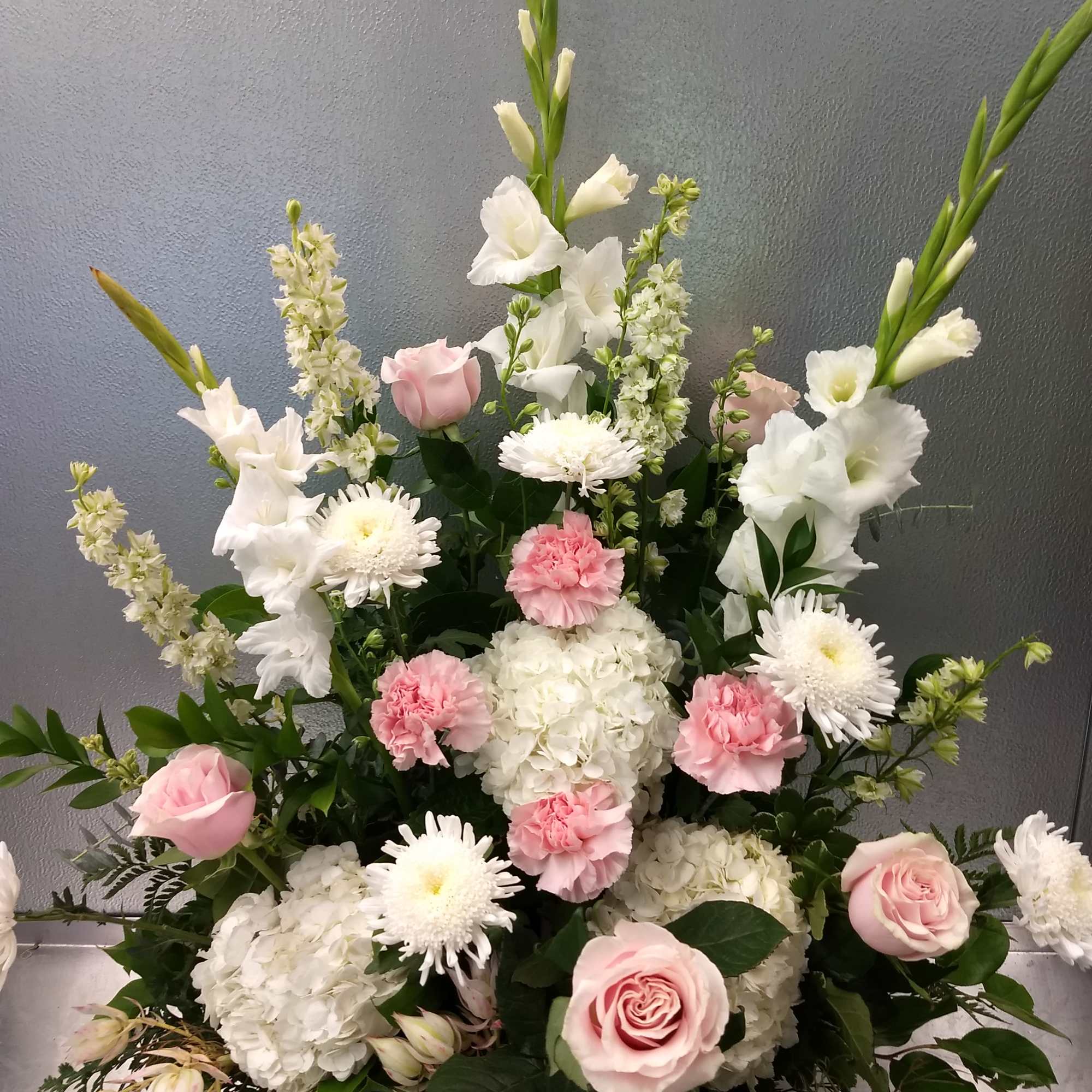 Pink roses, white hydrangeas, and white daisies in a tall arrangement