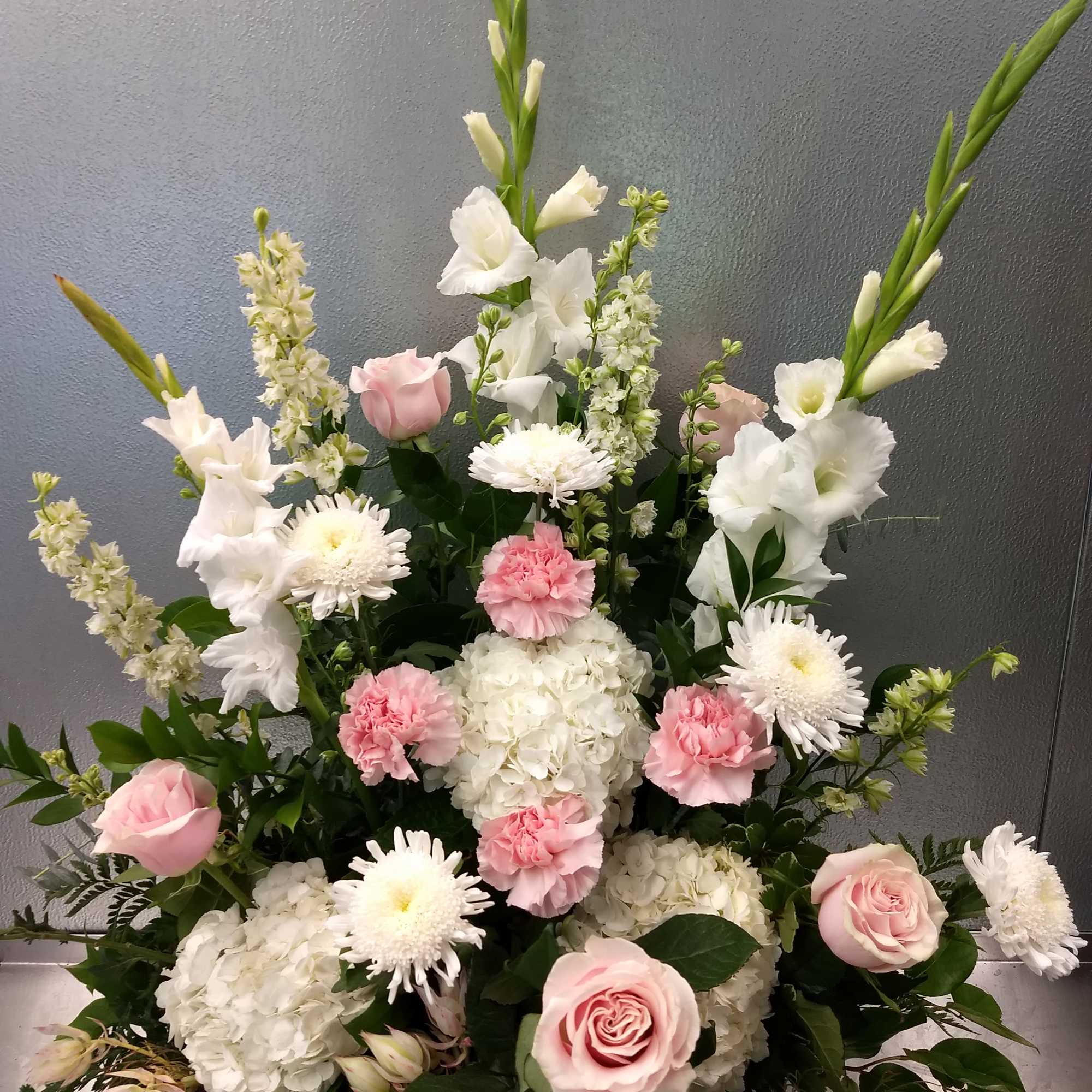 Tall floral arrangement with pink and white roses, hydrangeas, and white gladiolus