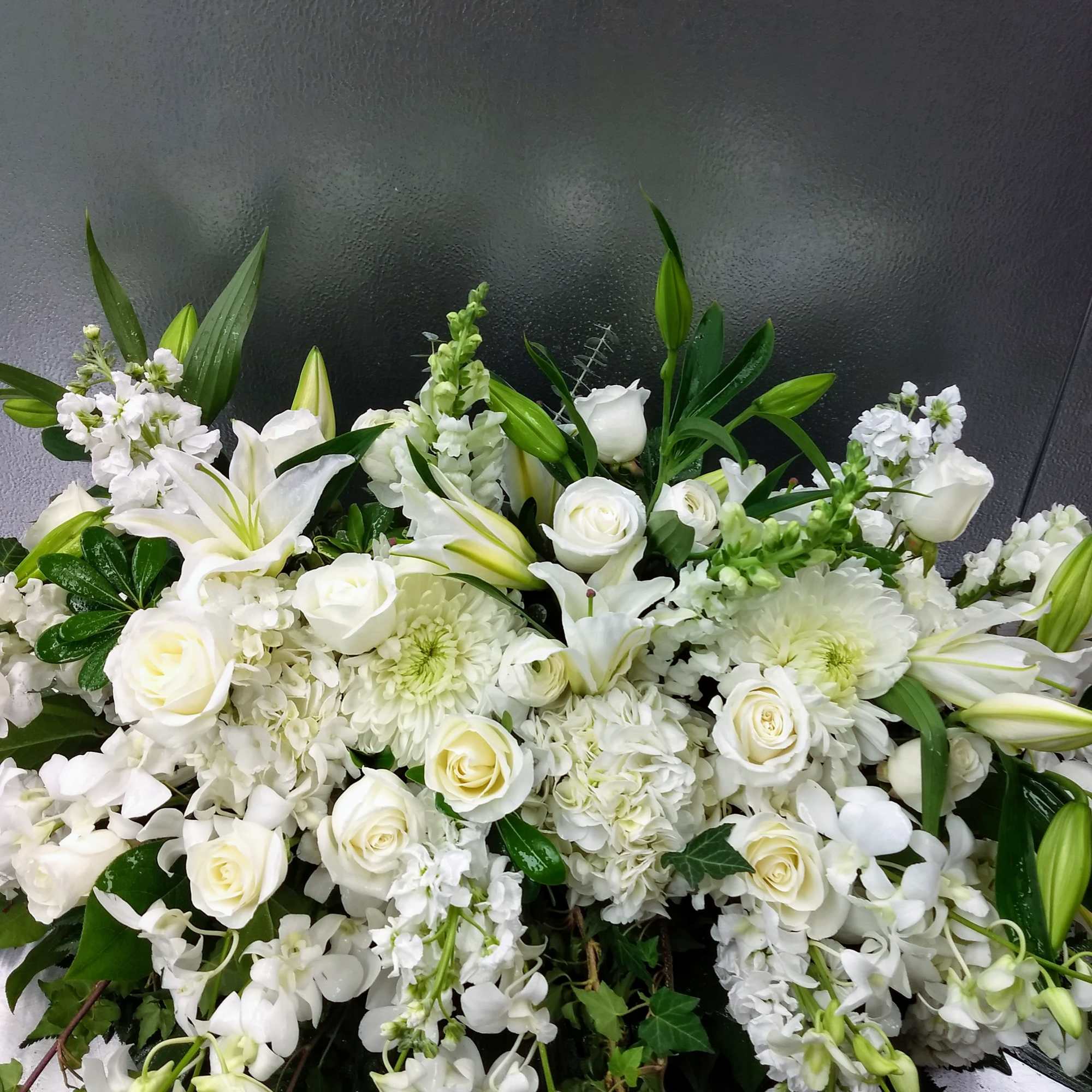White floral arrangement with lilies, roses, and orchids