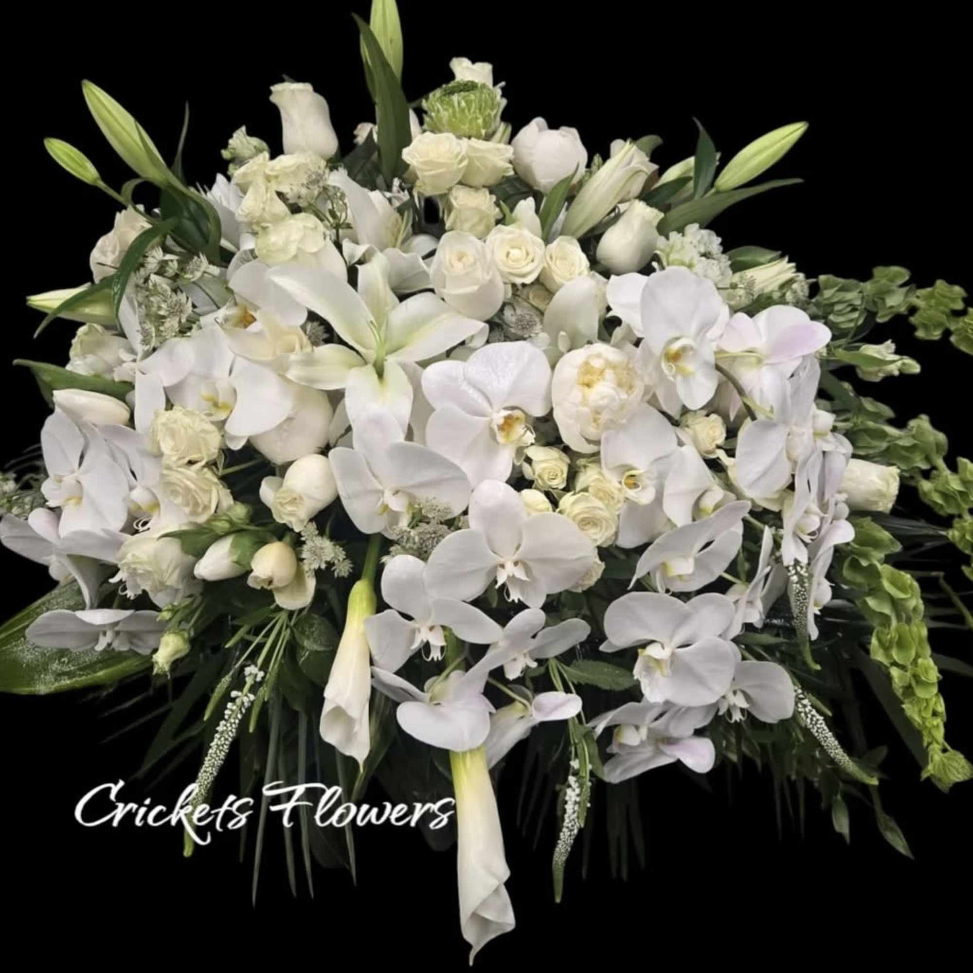 Large white floral arrangement with orchids, lilies, and roses
