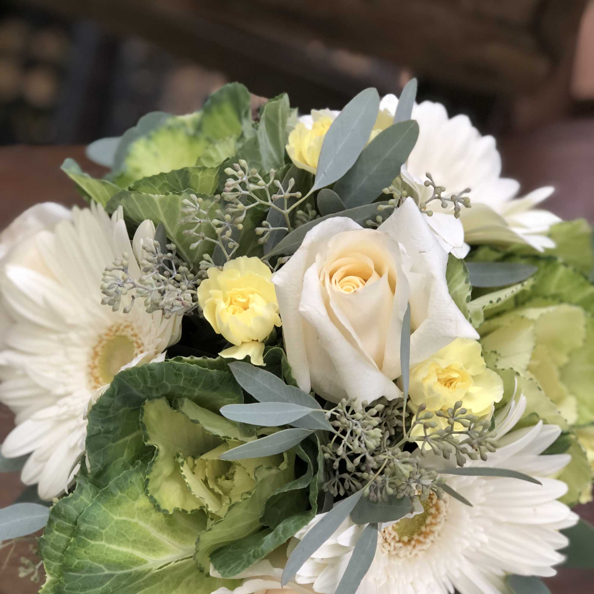 Bouquet of white daisies, cream roses, and green cabbage leaves