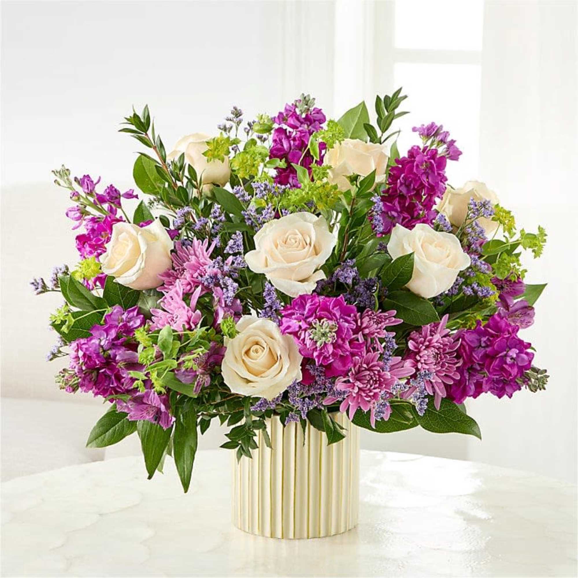 Creamy white roses set against vivid purple stock-like blooms and soft pink