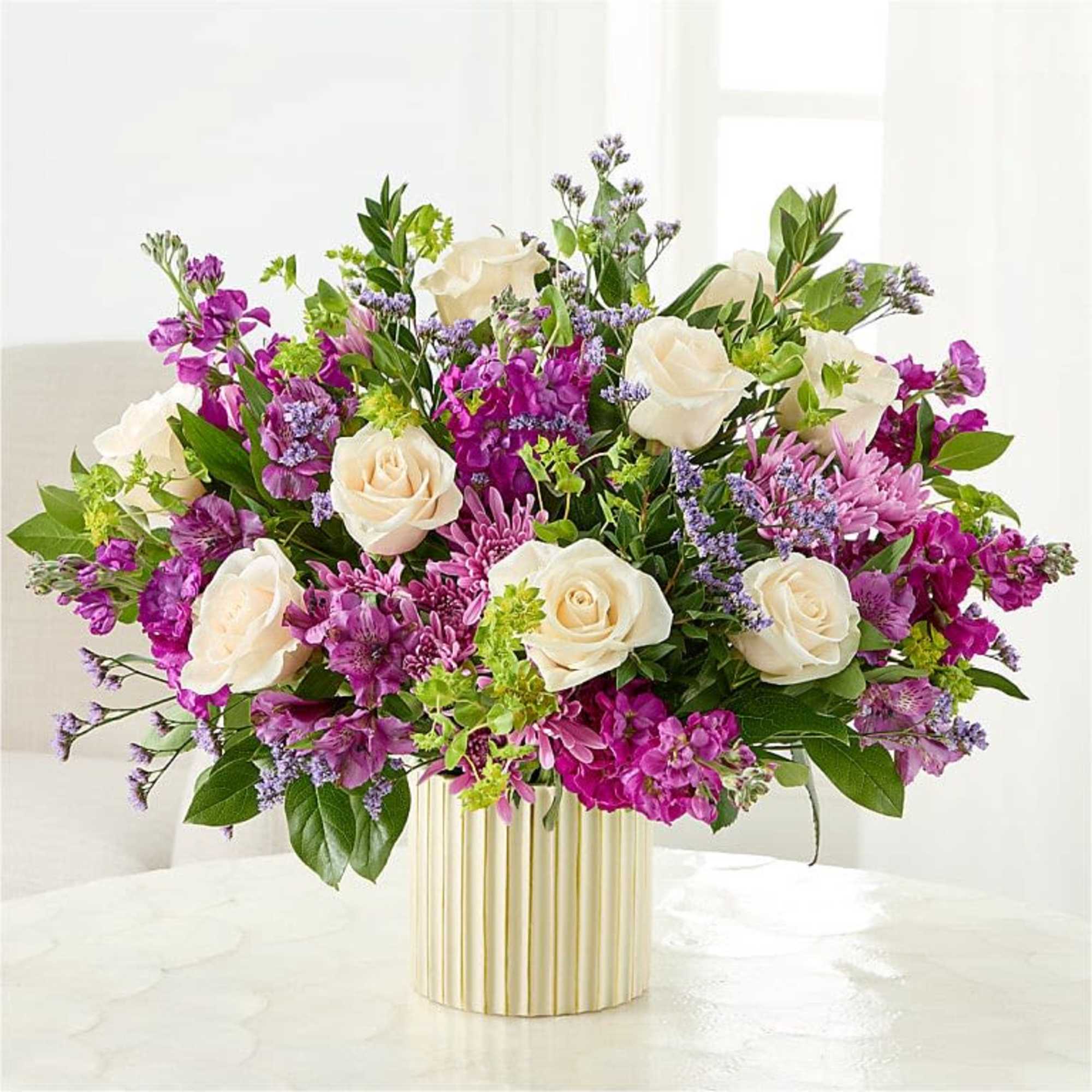 Creamy white roses set against vivid purple stock-like blooms and soft pink