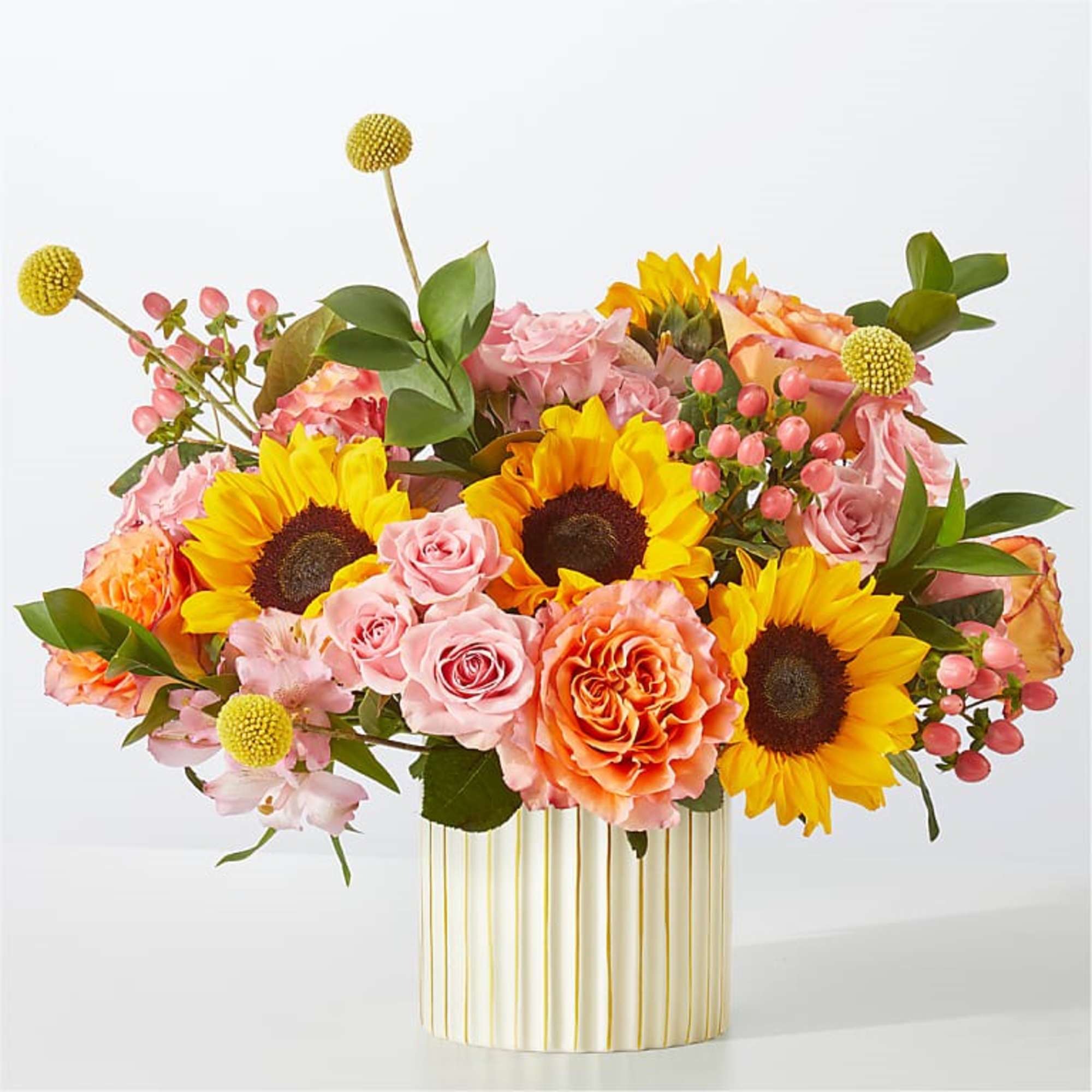 Bouquet of sunflowers, pink roses, and orange blooms in a striped vase