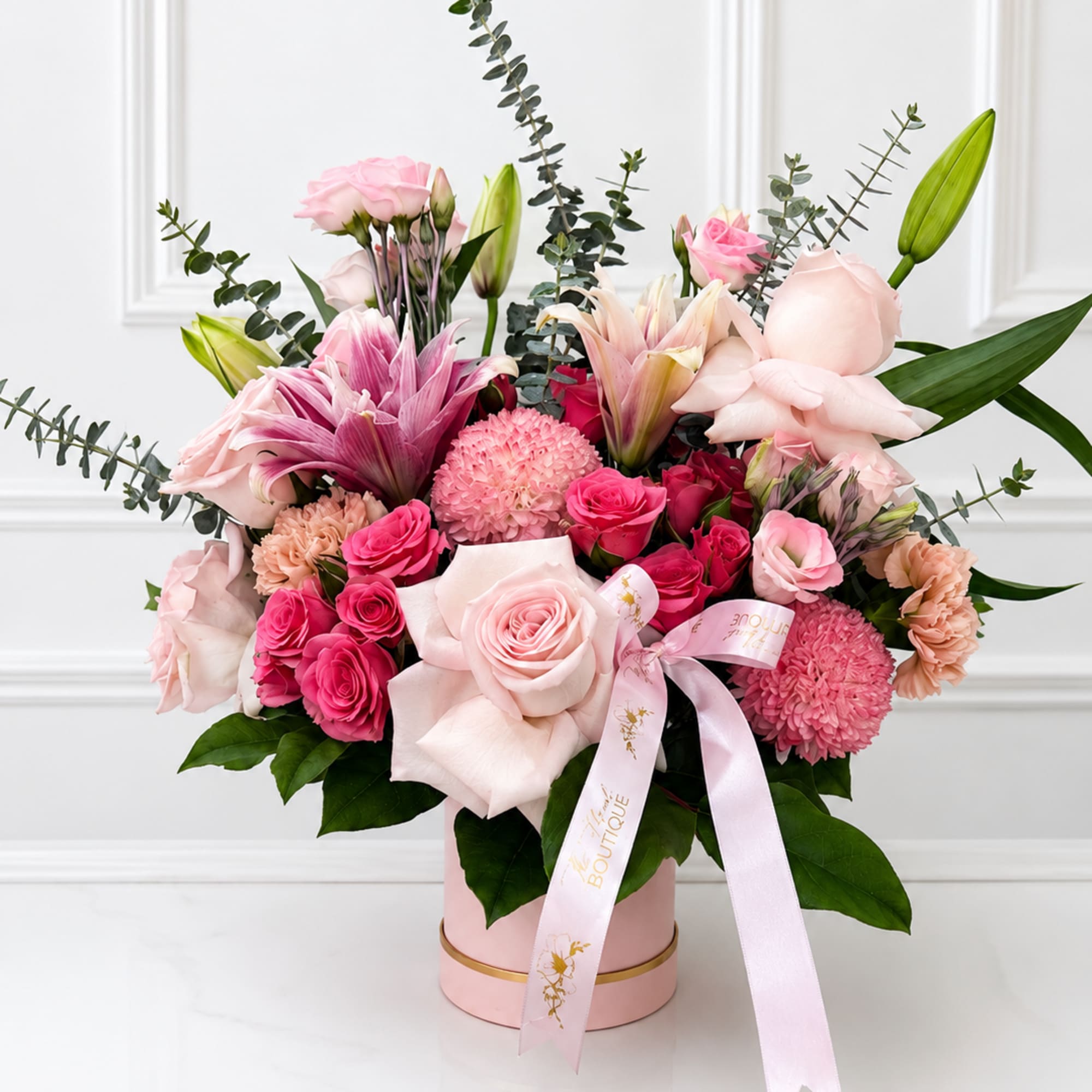 Pink and white mixed flower arrangement in a round box with a ribbon