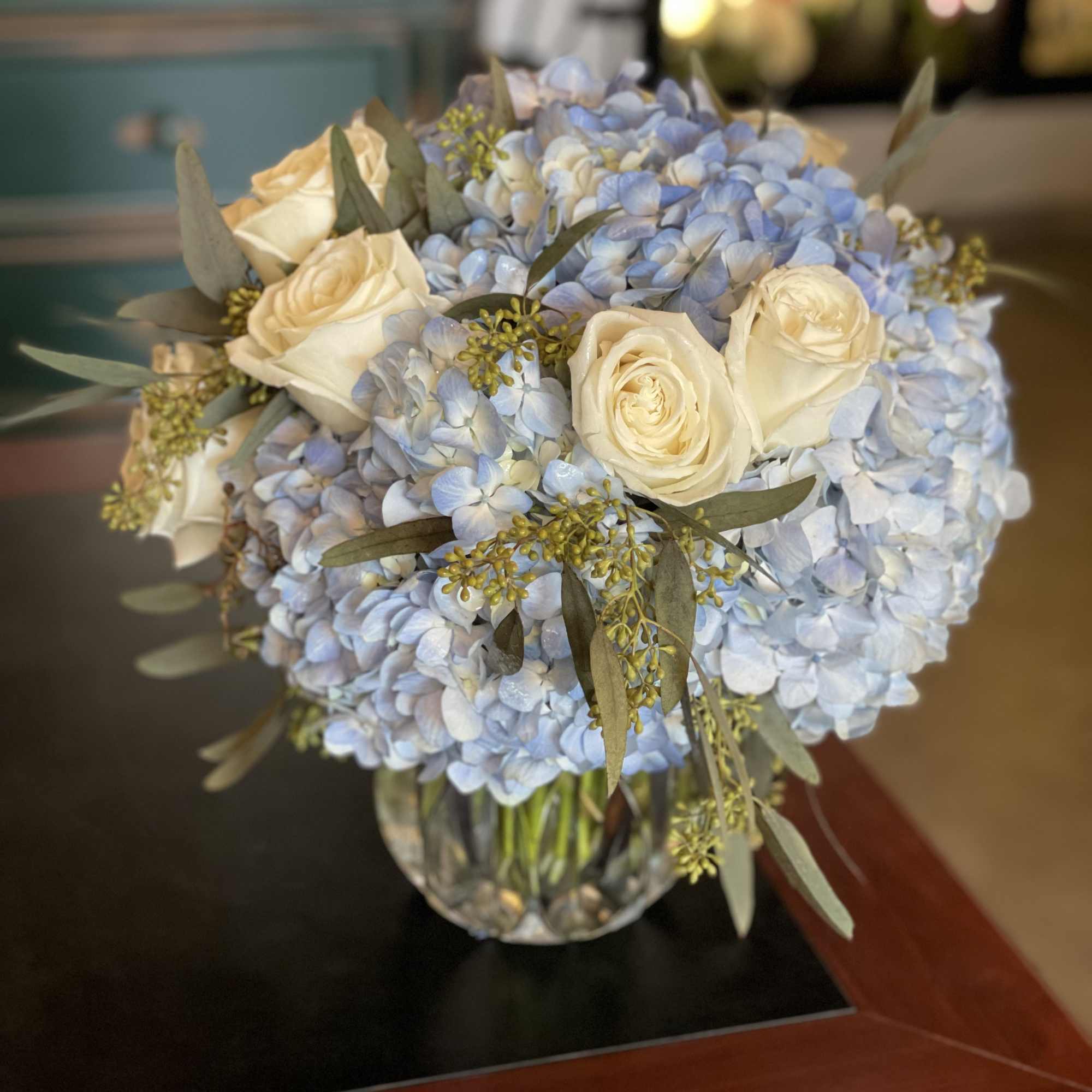 Blue hydrangea and white rose bouquet in a glass vase