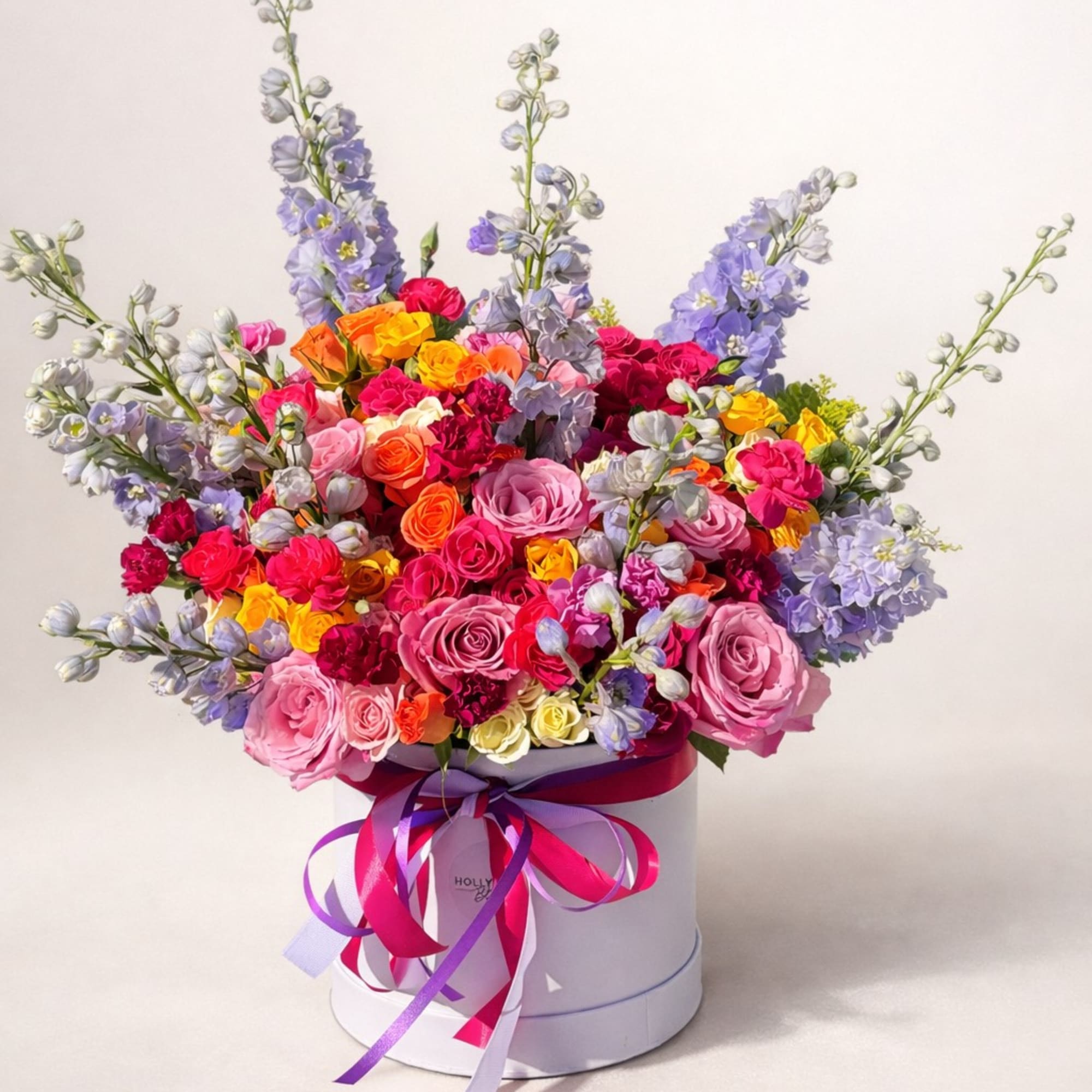 Colorful bouquet of roses and lavender flowers in a white hat box