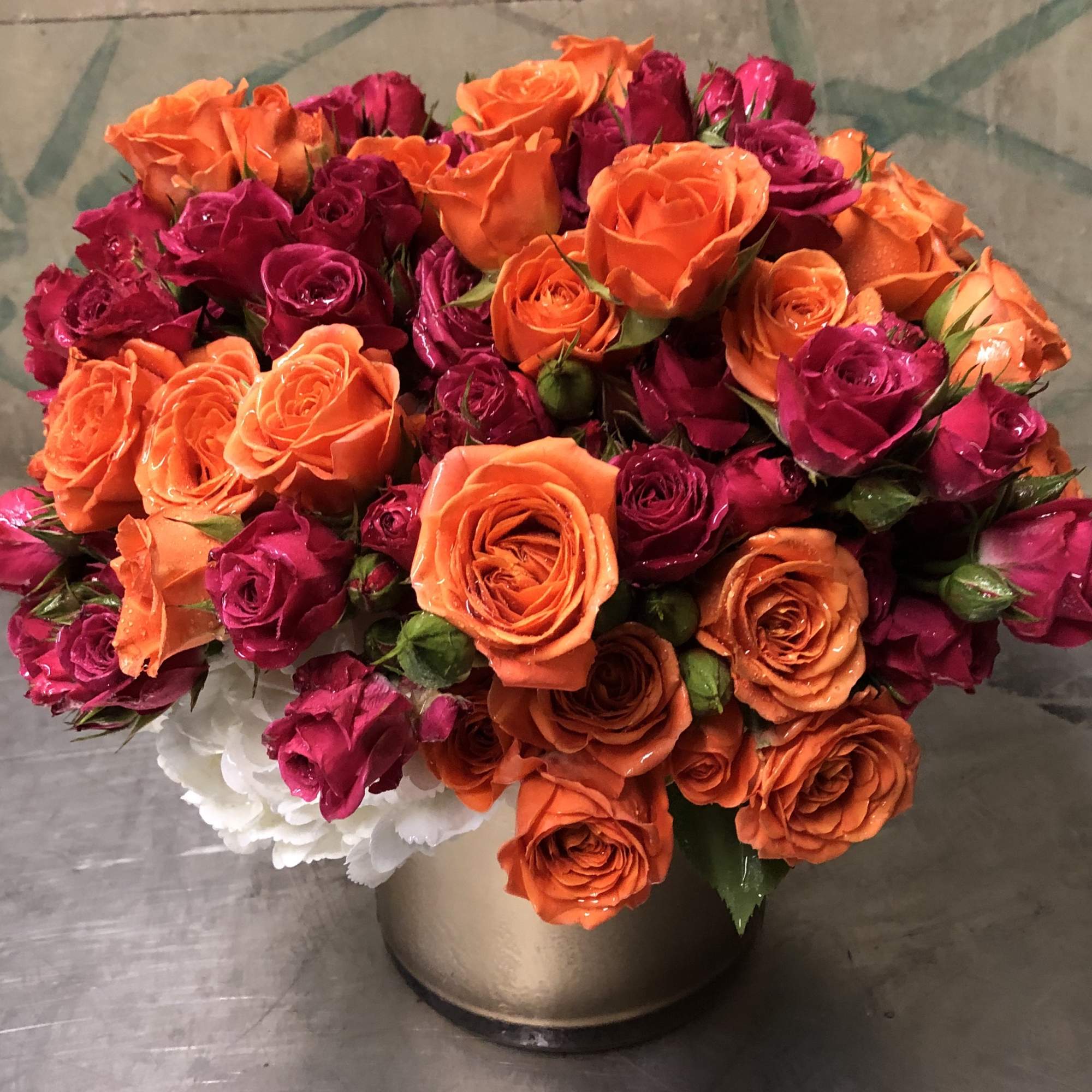 Bouquet of orange and magenta roses in a metallic vase