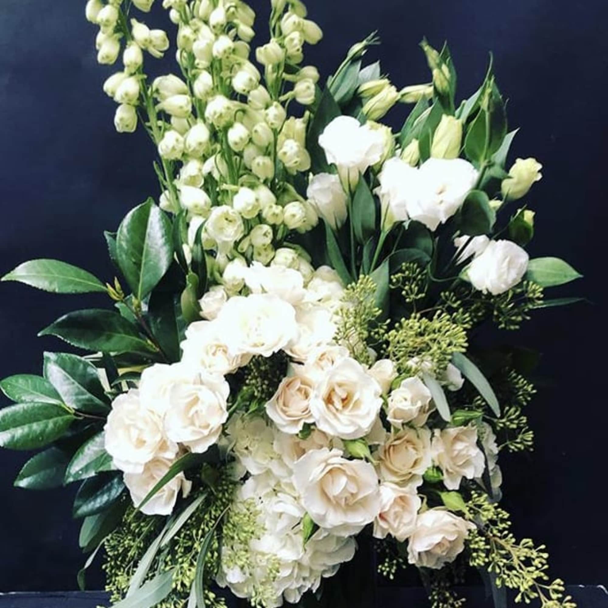 Tall white floral arrangement with roses and cascading blooms