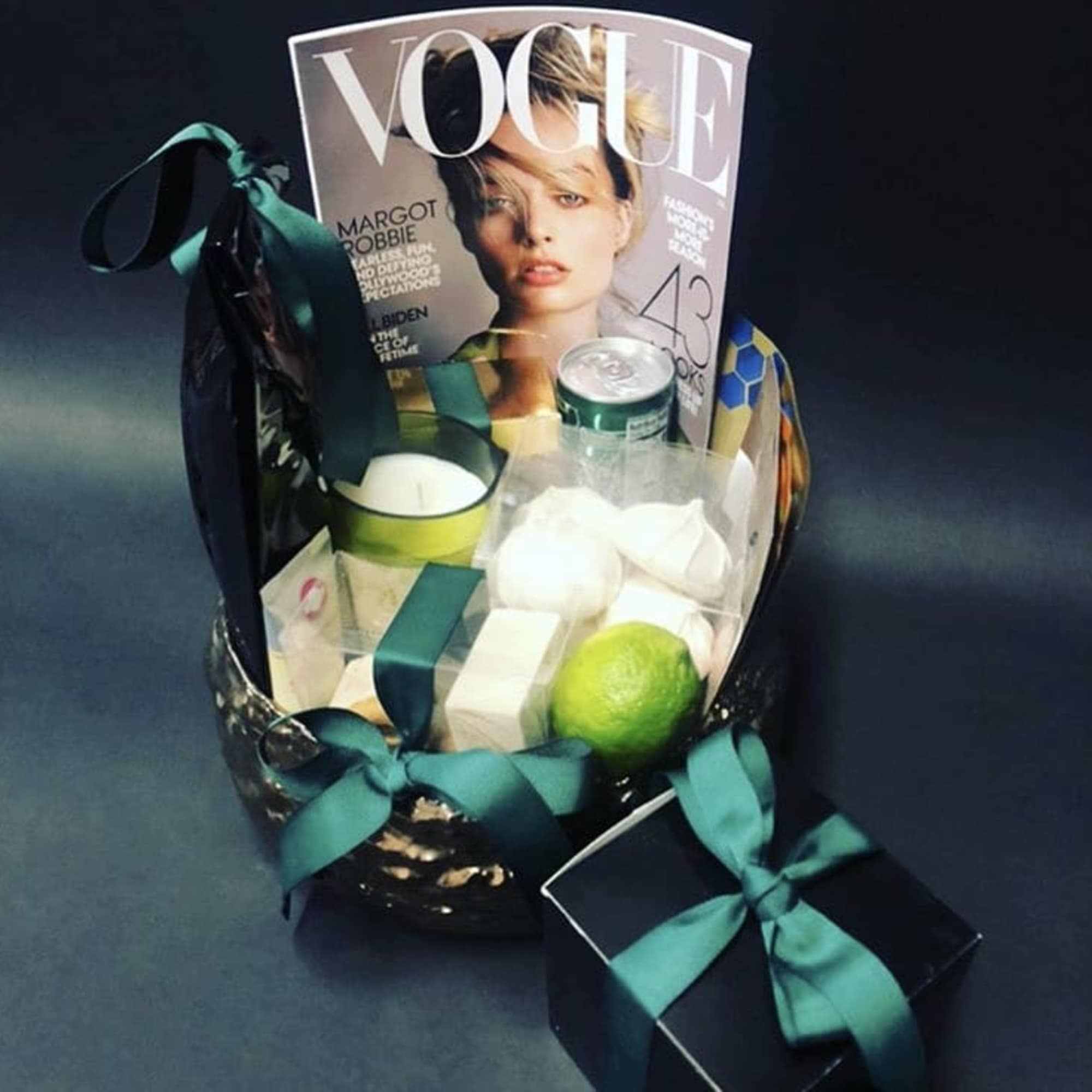 Gift basket with a Vogue magazine, candle, and boxed items tied with teal ribbon